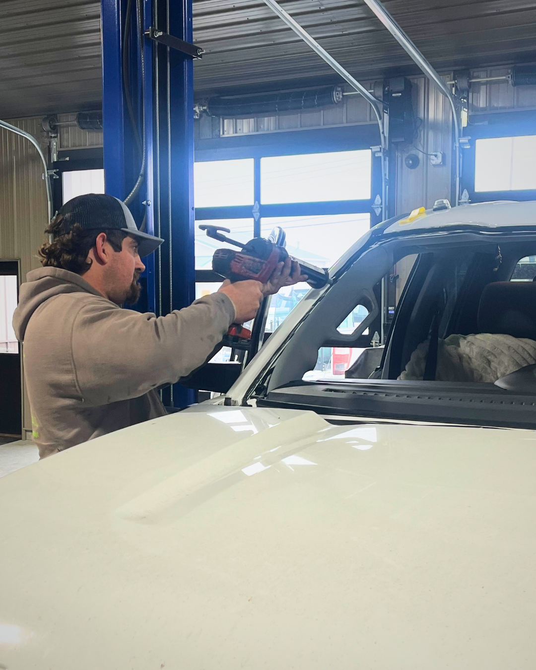 Image of glass repair technician caulking vehicle for a new windshield