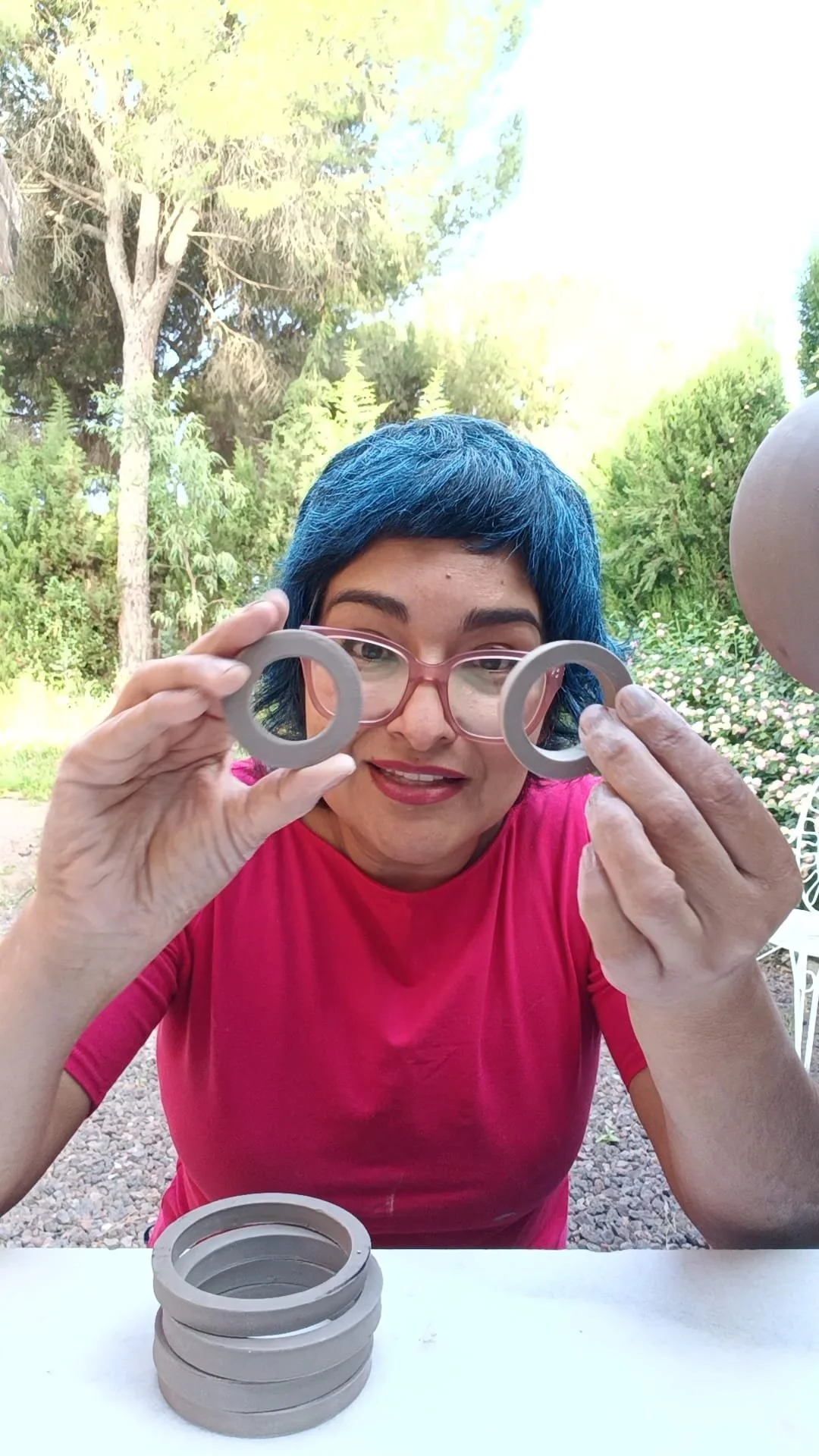 Blue haired artist holding two clay circles