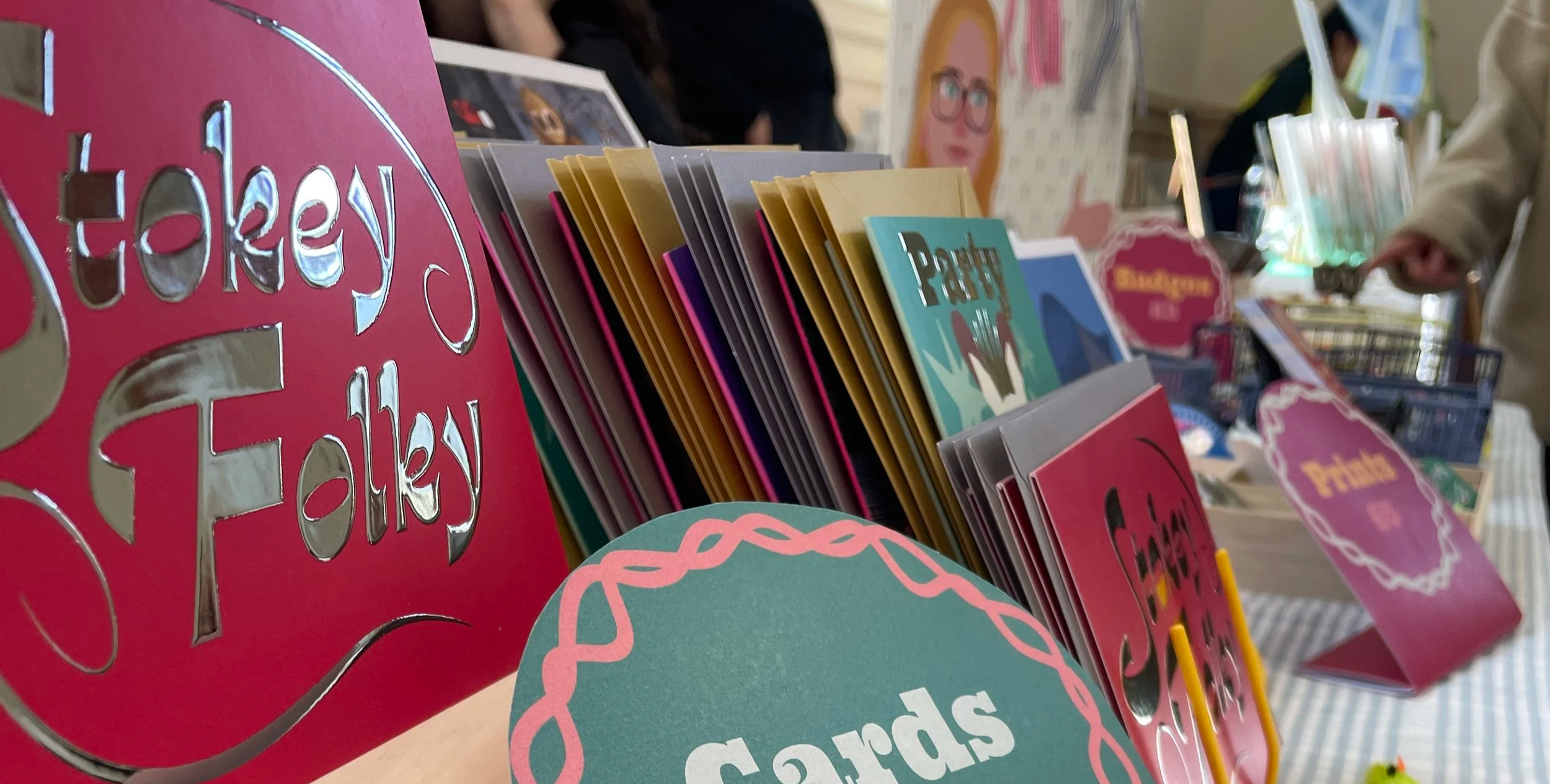 Close-up of a display of colorful greeting cards on a table at a card shop or market.