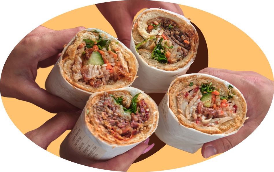 Four hands holding Banh Mi Boy sandwiches with meat, vegetables, and greens, with a yellow background.