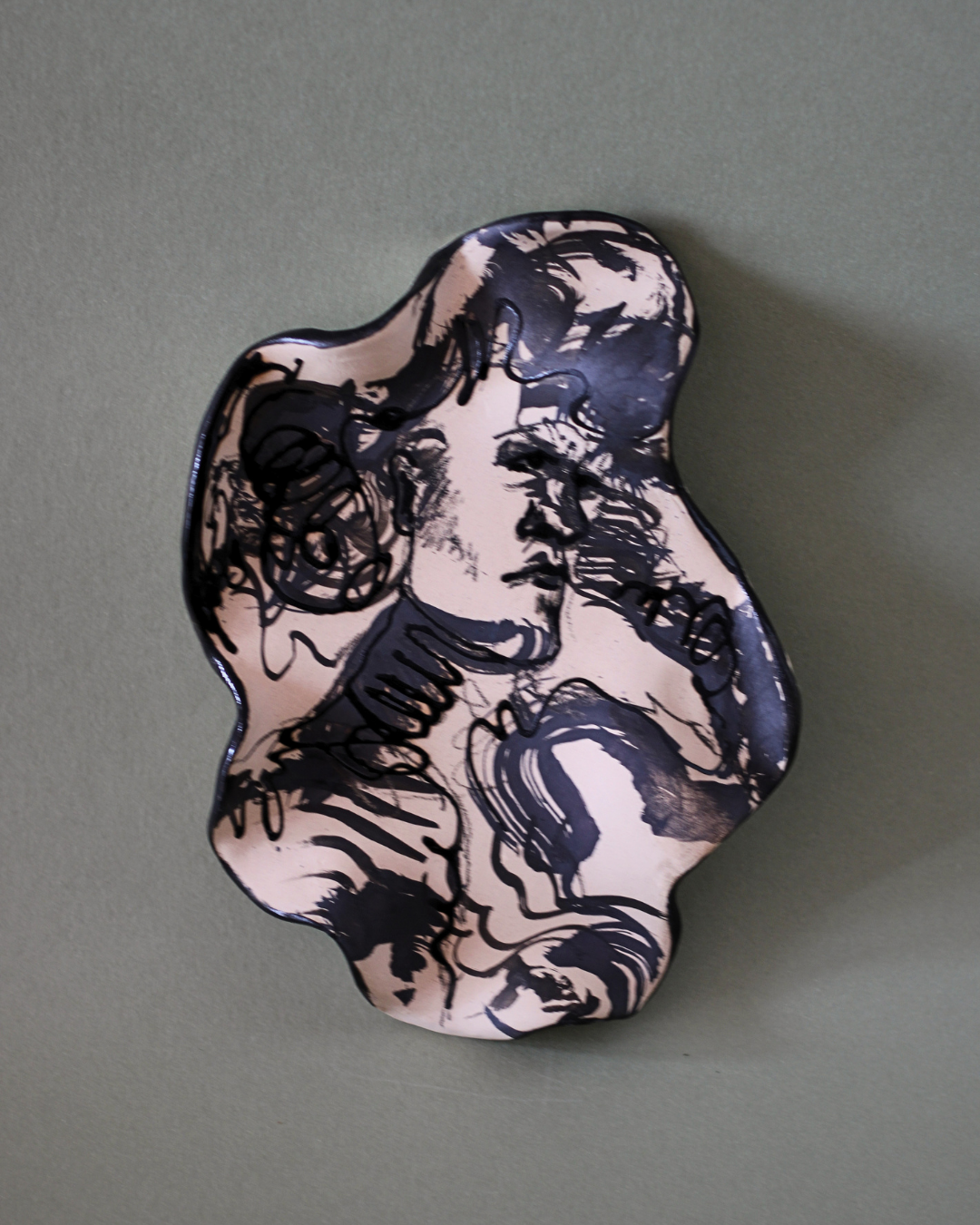 Hand-built illustrated ceramic plate featuring an abstract face and portrait motif with flowing linework, marbled glazes and handcrafted ceramic surfaces.