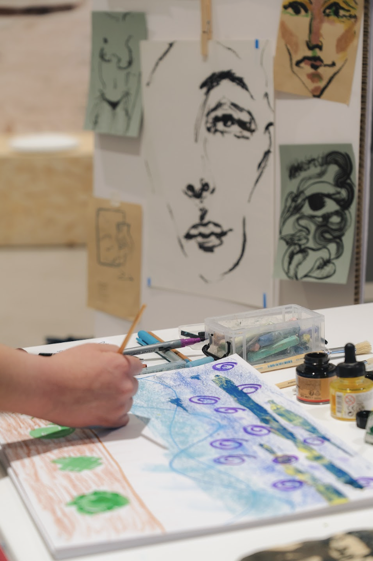 Creative workshop during La Genia Showroom, featuring drawing materials and artworks displayed as part of an event celebrating emerging female artists in Barcelona.