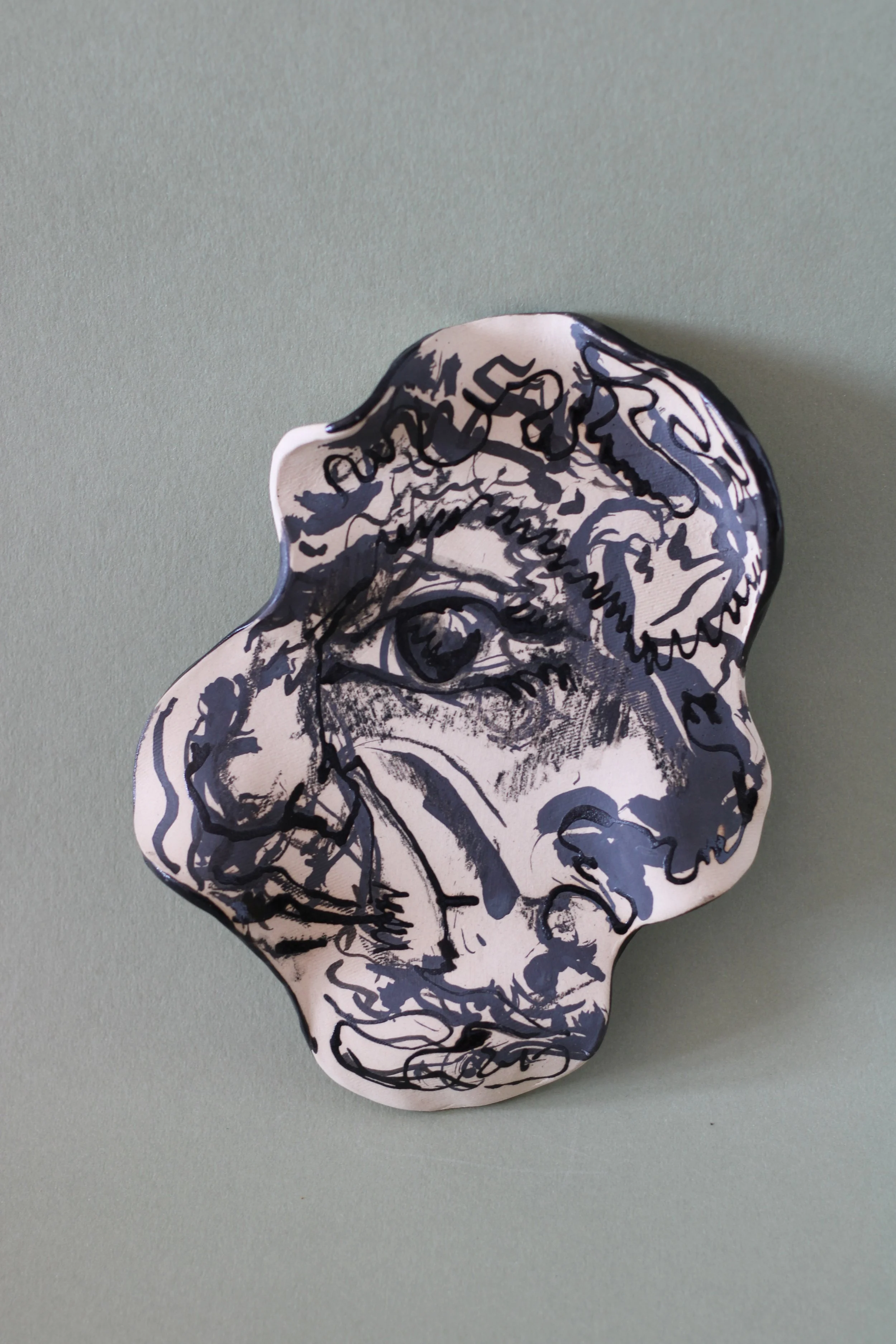 Detail of the hand-drawn eye motif, flowing linework and marbled ceramic glazes on the plate.