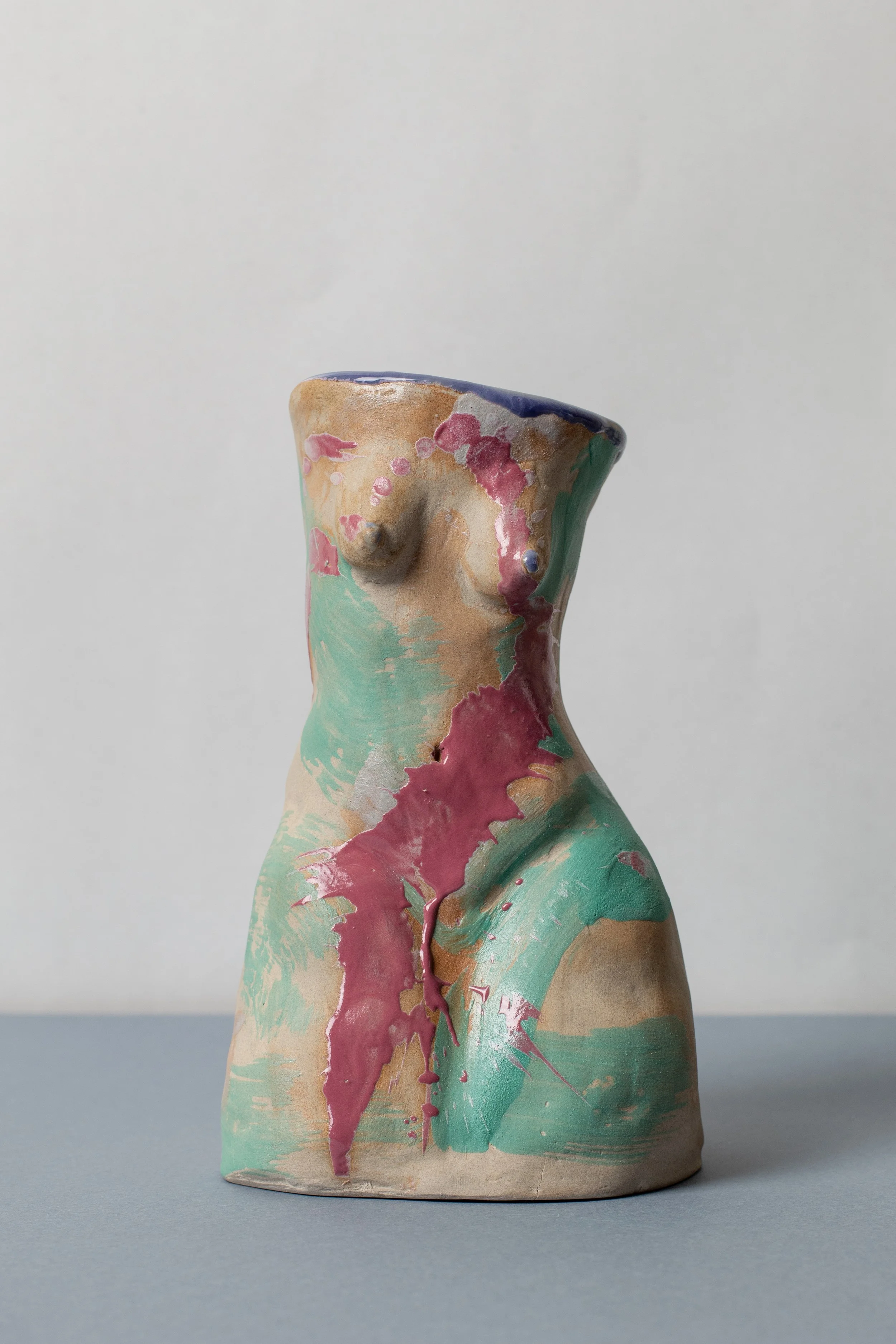 Sculptural ceramic candleholder inspired by the female figure, featuring expressive green and pink glazes and organic sculptural curves.