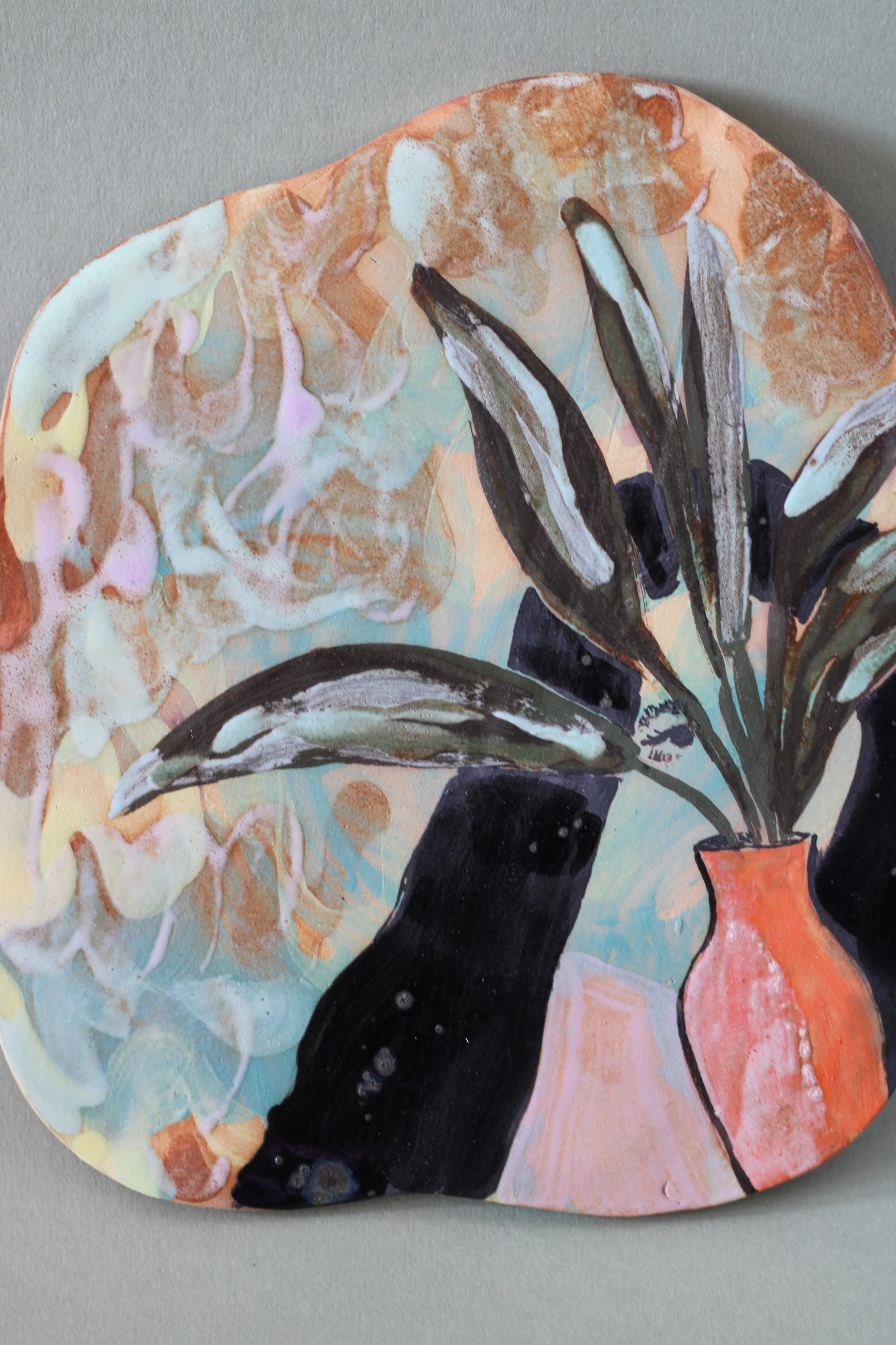 Detail ceramic wall piece featuring a botanical still life with dark leaves, a pink and orange vase, and layered pastel-colored glazes.