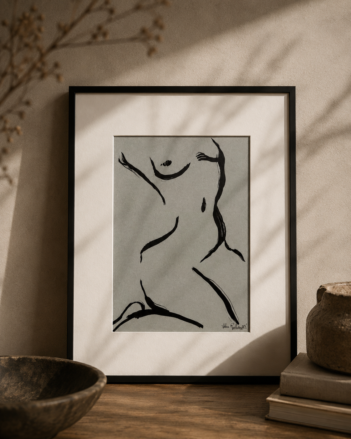 Brushwork drawing depicting a female figure through bold black gestural lines on a white background displayed in a black frame in a living-room.