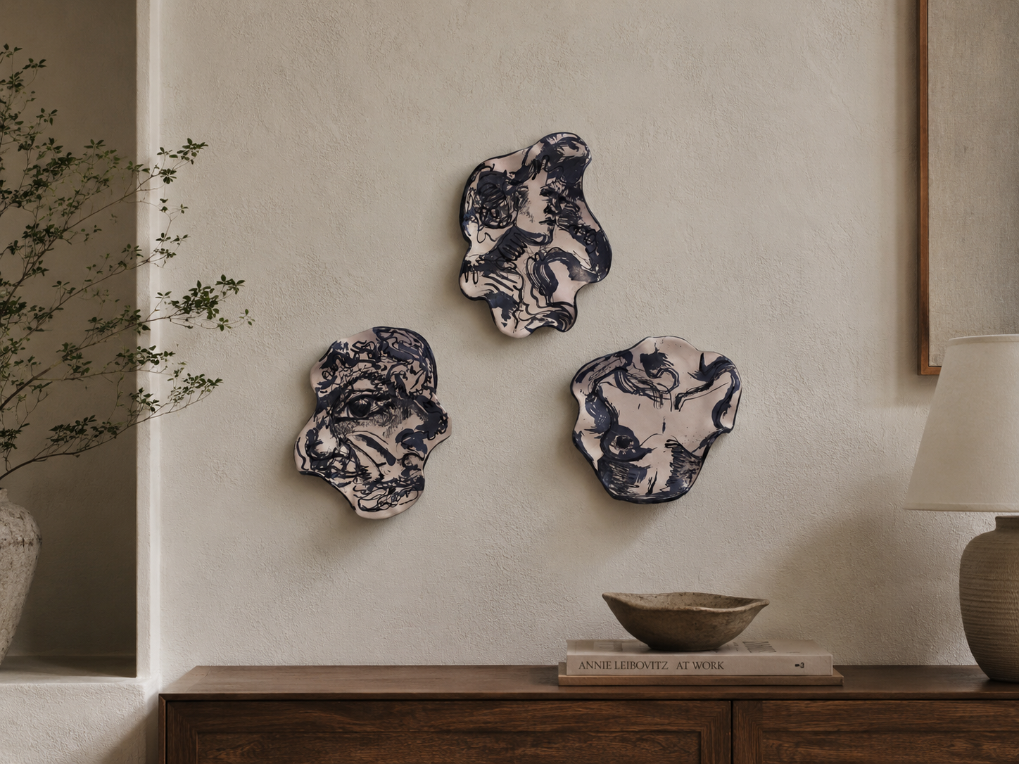 Display of three hand-built illustrated ceramic plates featuring diffrent ilustrated motif with flowing line work, marbled glazes in a living room.
