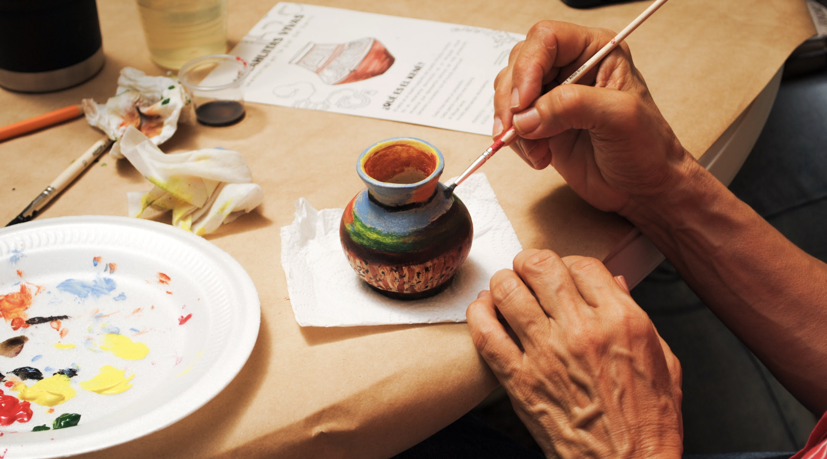 Close-up of the ceramic painting process in Valeria R.O.'s Mocahuitas Workshop, showing a handcrafted vessel being finished with colorful brushwork by a participant.