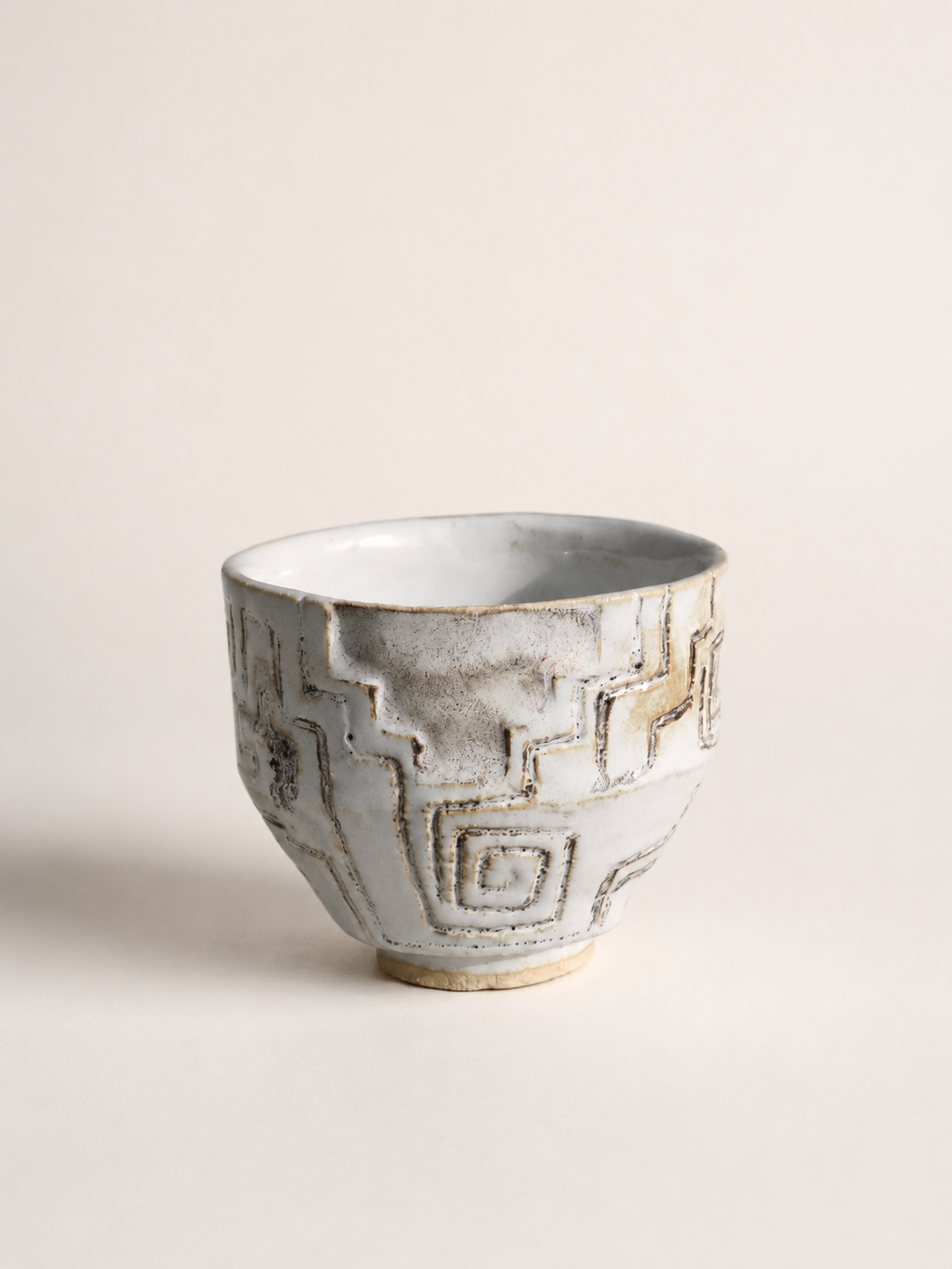 Hand-built ceremonial ceramic matcha cup featuring carved kené-inspired patterns, layered ceramic glazes and an organic sculptural silhouette.