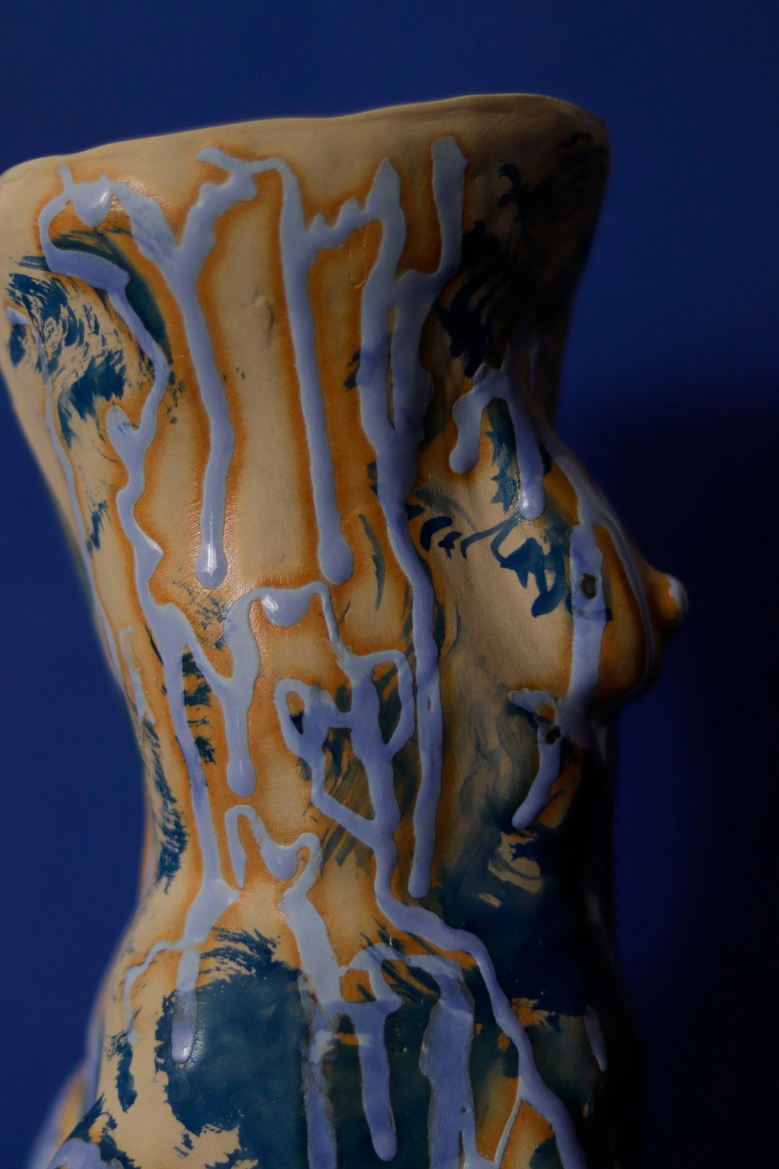 Detail of side profile of sculptural ceramic vessel inspired by the female figure, featuring expressive blue dripping glazes and organic sculptural curves.