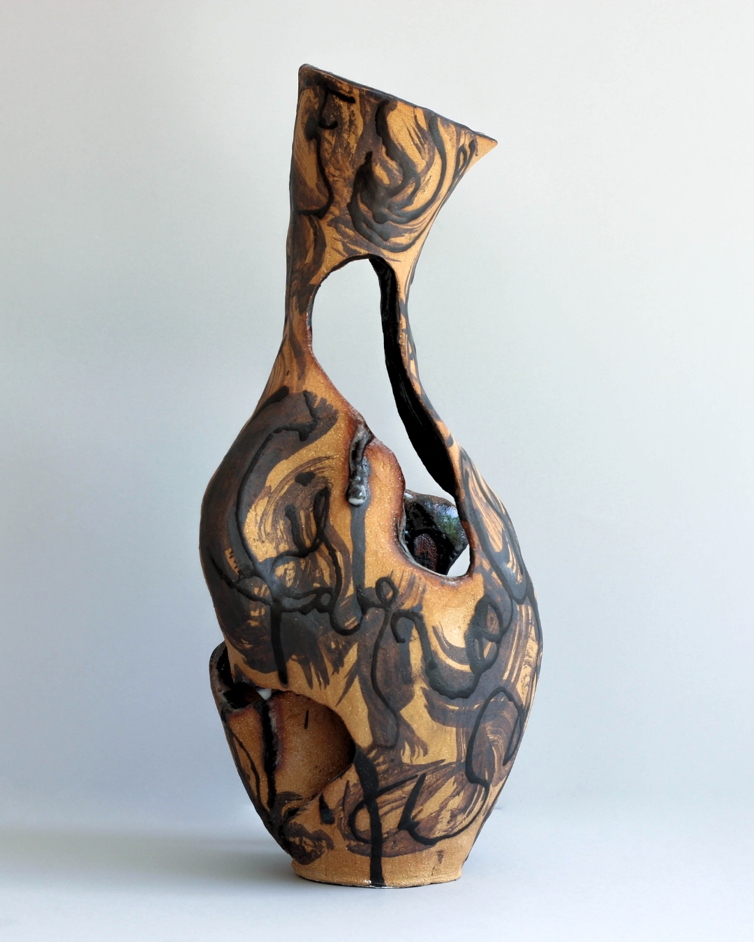 Hand-built ceramic vessel with an elongated sculptural form, large organic openings, and flowing black glazes inspired by the Ucayali River