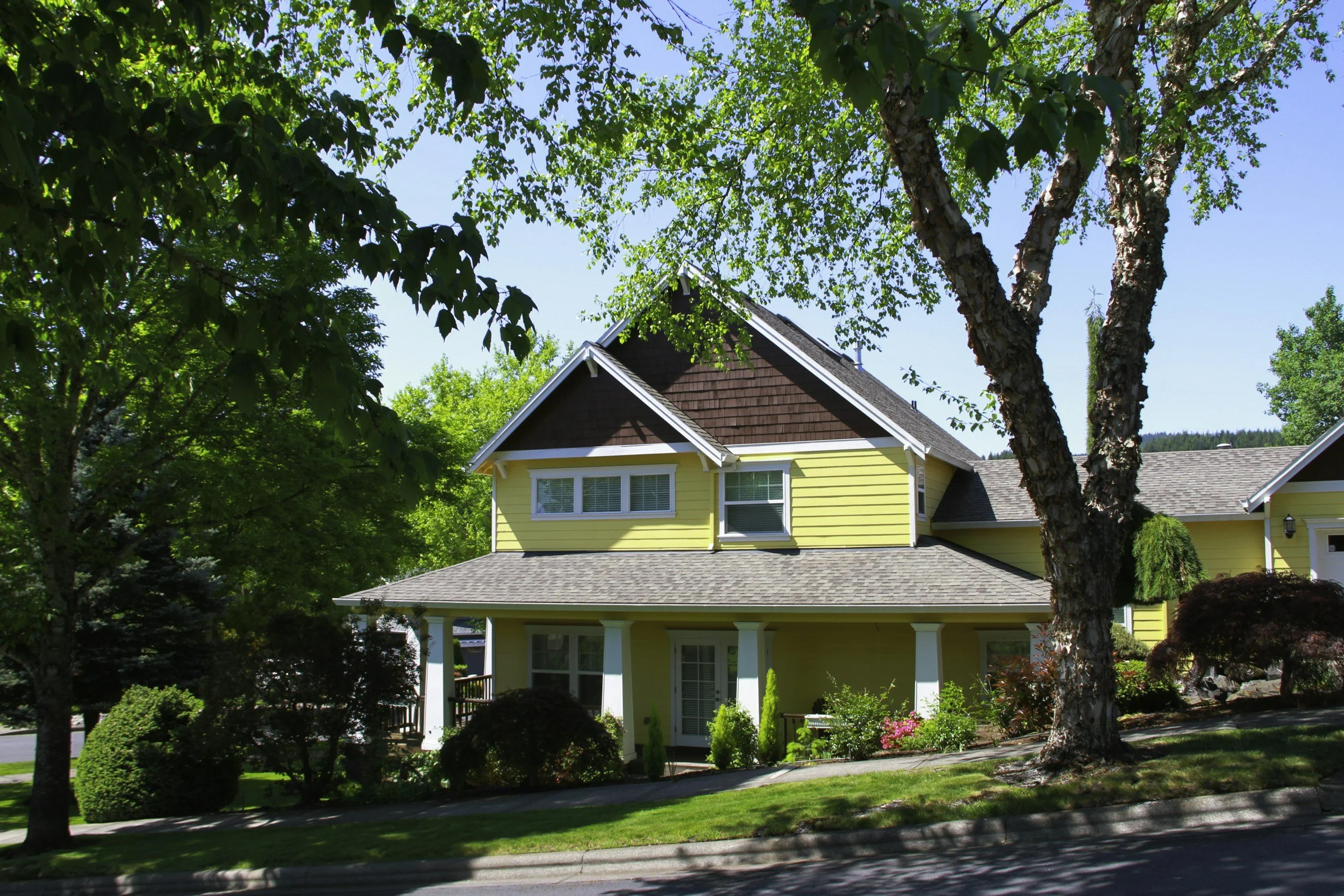 yellow and brown craftsman home with blue sky and green vegetation