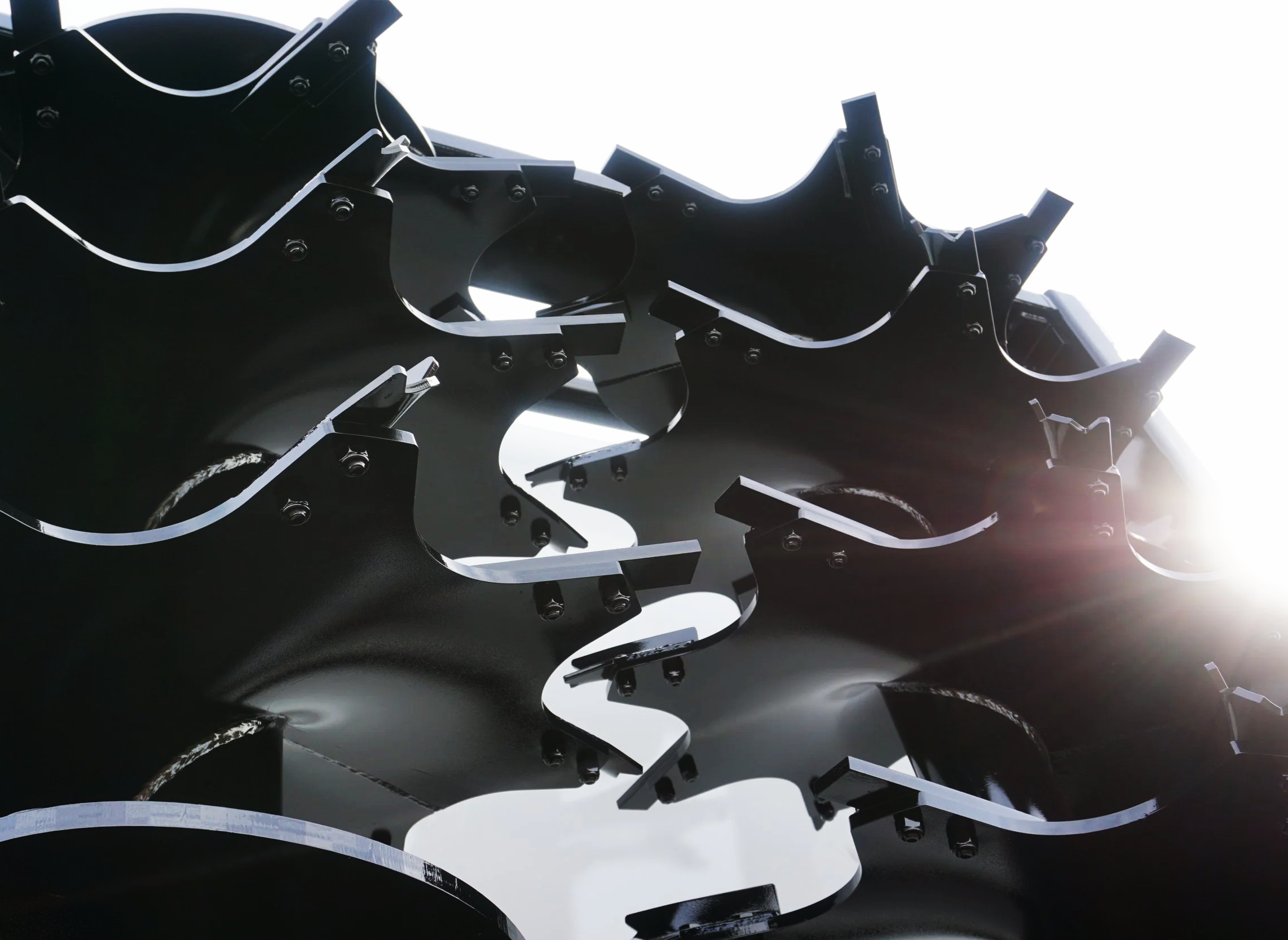 Close-up of a metallic mechanical component with interconnected black parts and visible bolts.