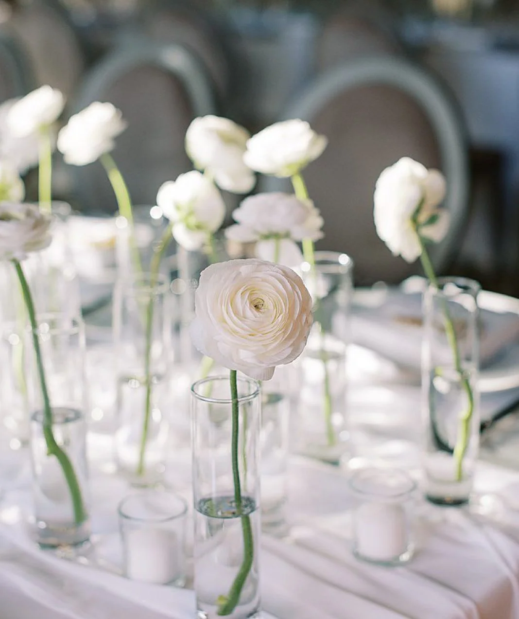 Elegant white floral table decor with single blooms in glass bud vases
