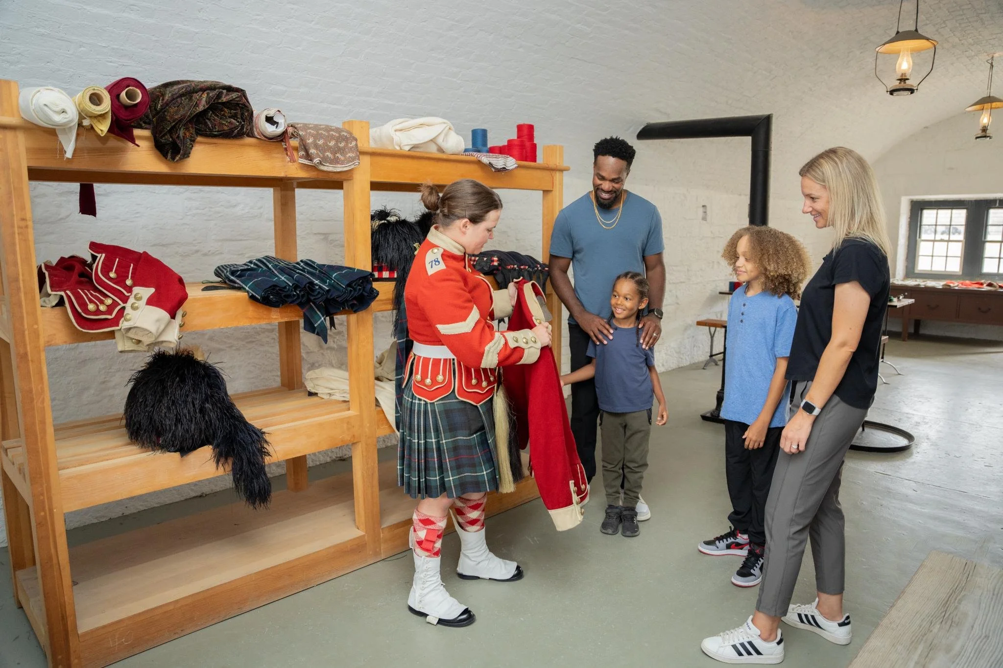 People shopping for vintage clothing in a store with wooden shelves and white brick walls.