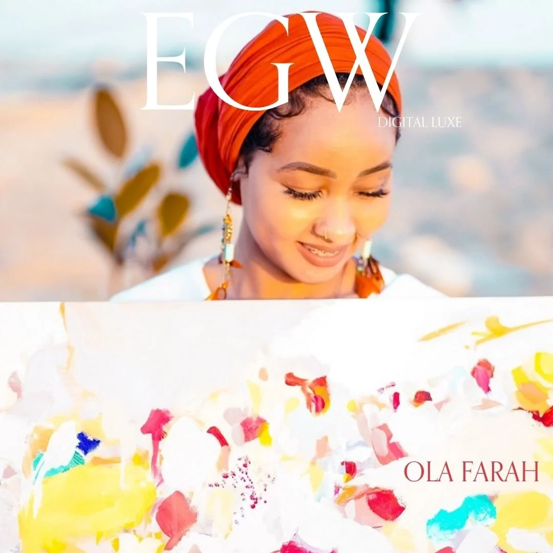 A woman with a light brown complexion, wearing an orange headscarf and earrings, holding a colorful abstract painting with her eyes closed and a gentle smile.