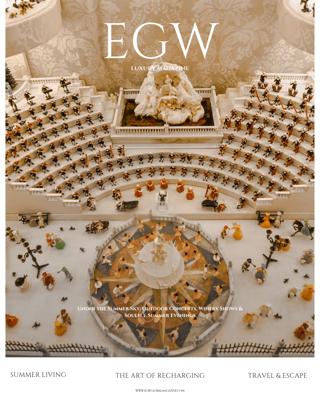 Decorative magazine cover featuring a miniature figurine scene of people attending an outdoor concert or event on a staircase with a fountain at the top. The scene includes tiny figures of musicians, dancers, and spectators, with trees, lampposts, an