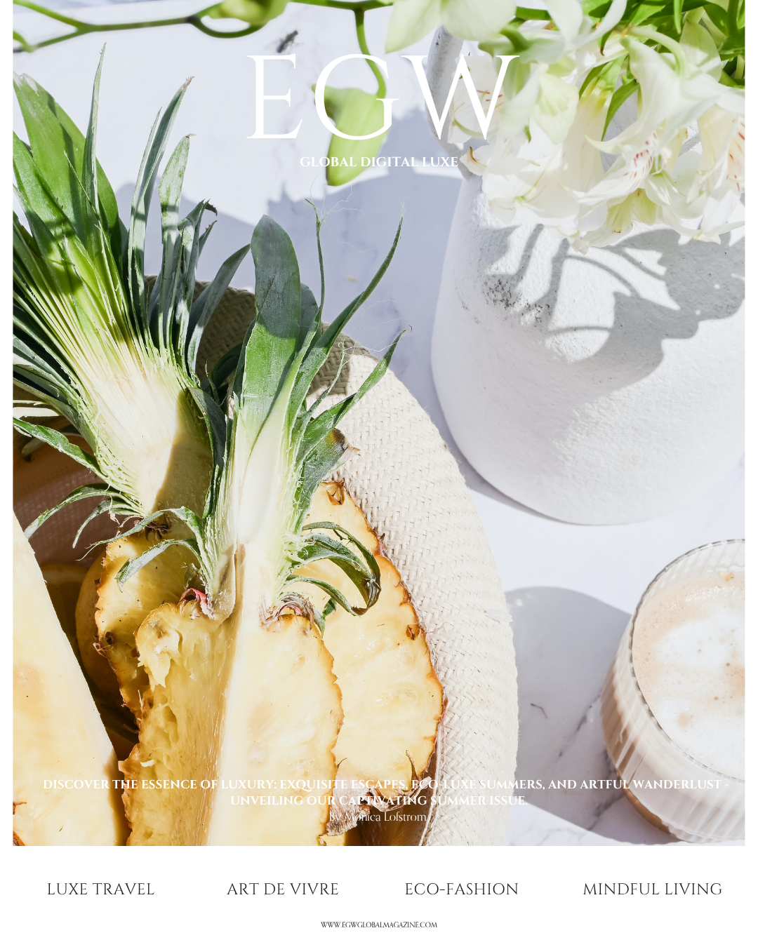 Close-up of a pineapple with its green leaves, next to a white vase with white flowers, and a drink in a glass on white surface.