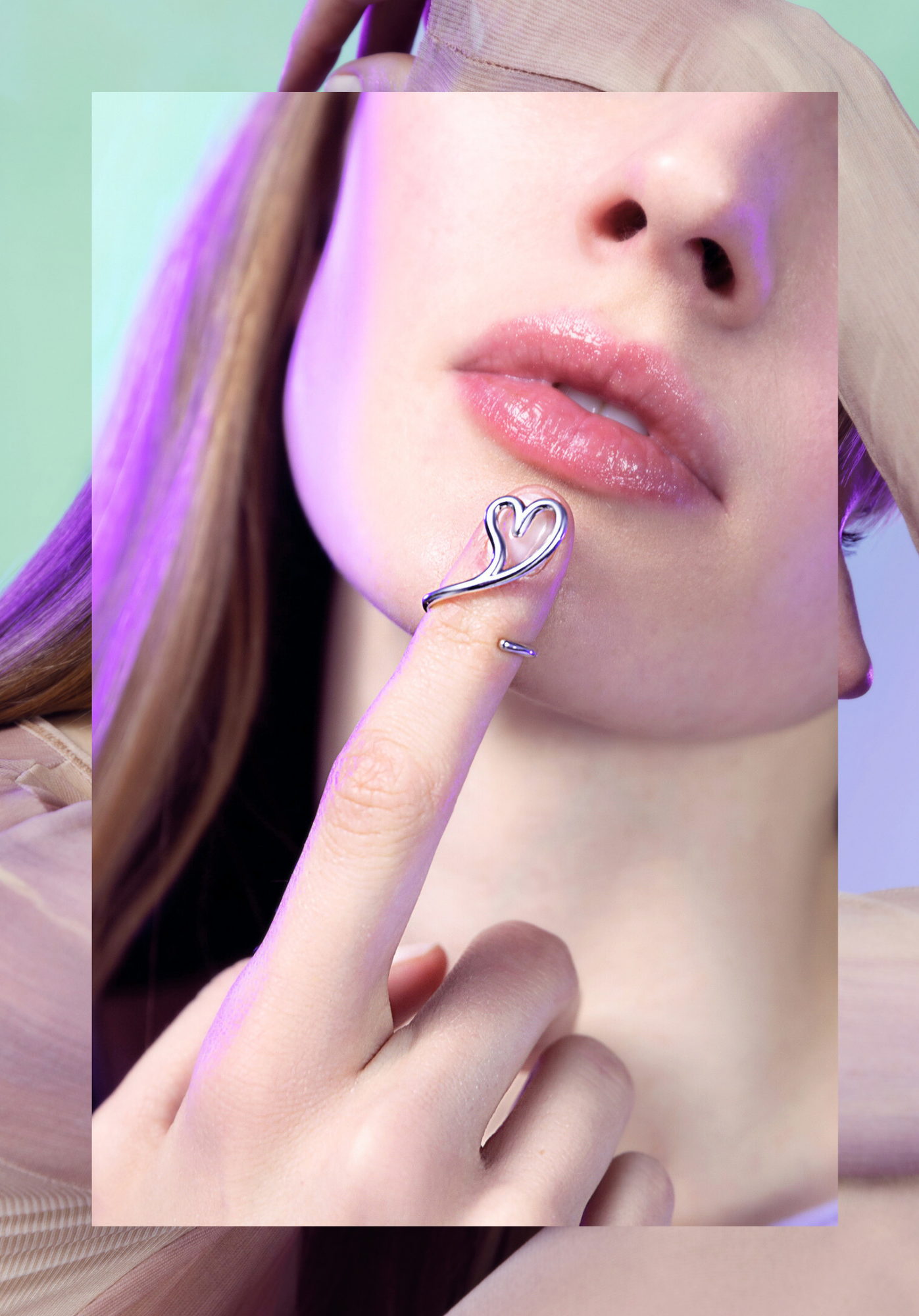 Close-up of a woman's lips, nose, and hand with a heart-shaped ring near her lips, with pastel-colored background.