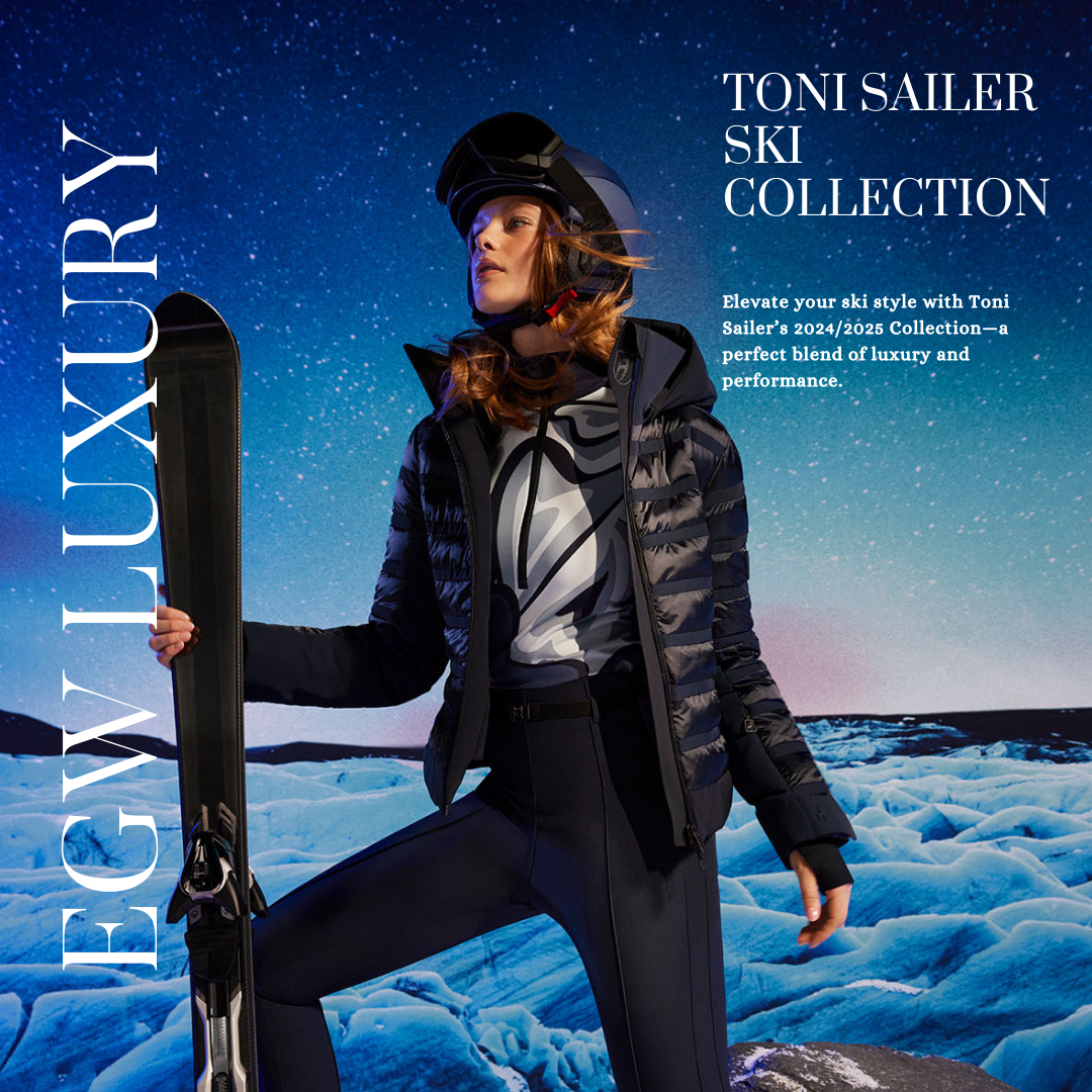 A woman dressed in ski gear holding a ski pole stands on a snowy landscape under a starry night sky, promoting Toni Sailer ski collection.