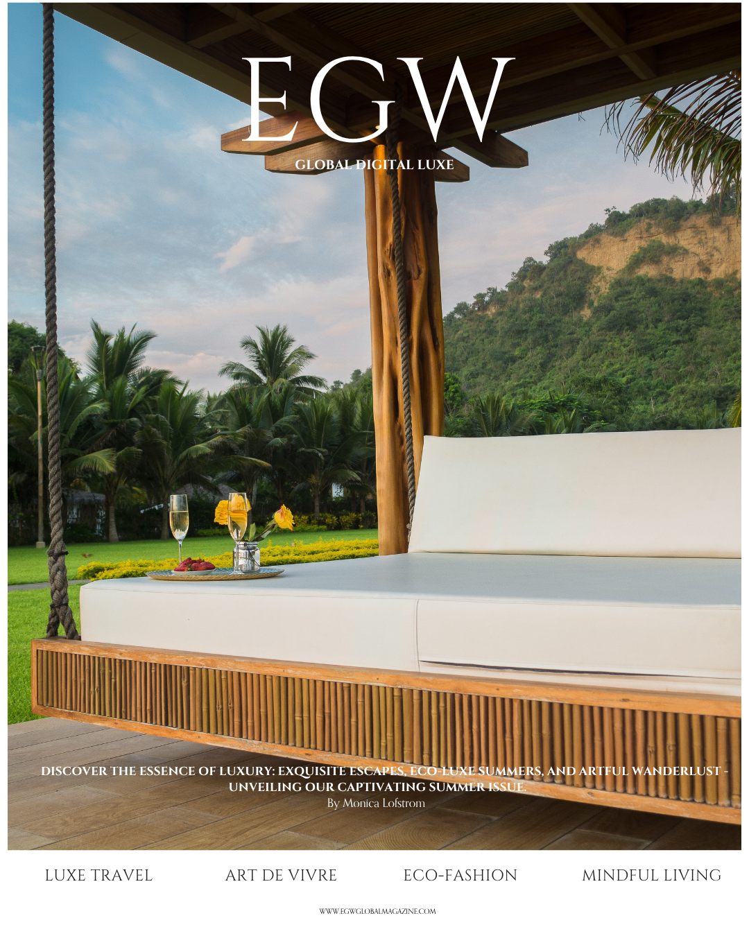 A luxurious outdoor lounge area with a white cushioned daybed with a wooden base, set against a scenic backdrop of lush green mountains and palm trees, featuring a tray with a glass of champagne, a glass of orange juice, and a bowl of strawberries on