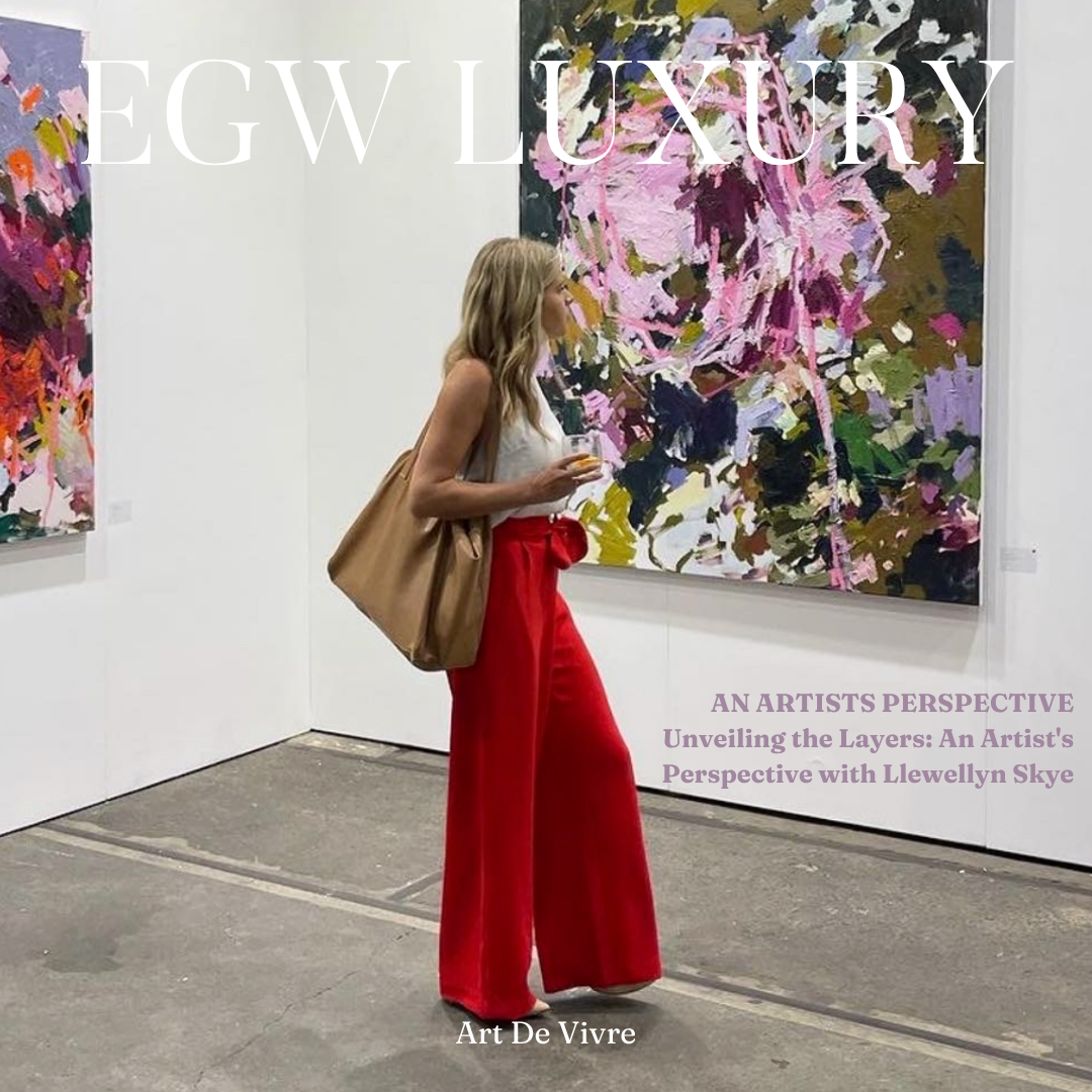 A woman with blonde hair, wearing a white top, red wide-leg pants, and carrying a large tan bag, is standing in an art gallery looking at an abstract painting with pink, purple, green, and black colors.