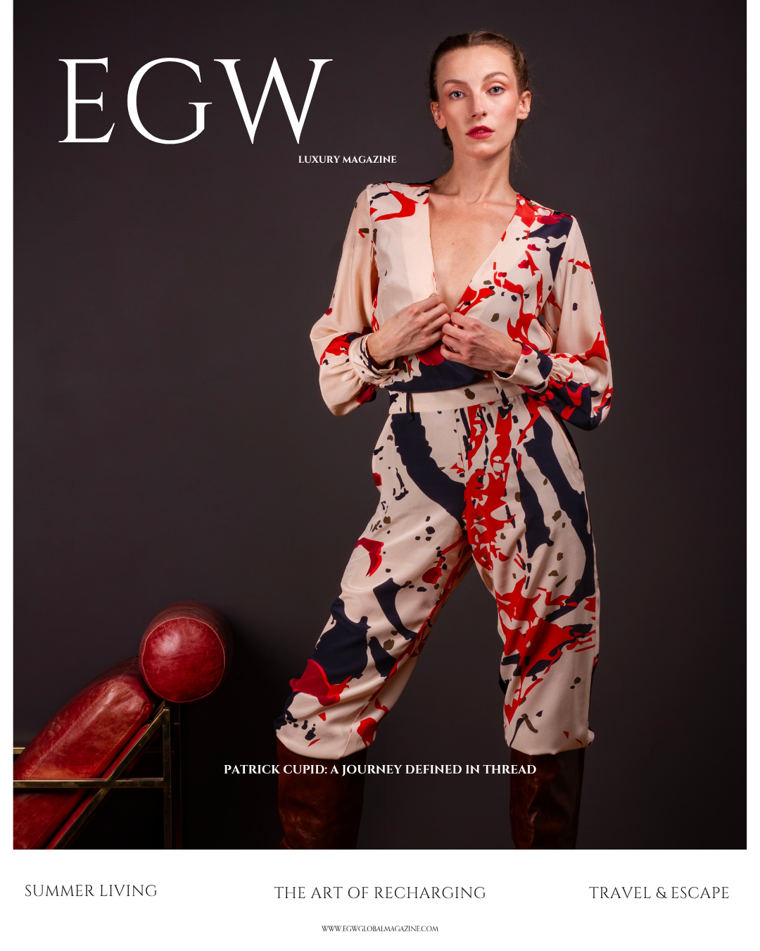 A fashion model in a beige, red, and navy abstract print outfit standing against a dark background, with a red leather chair on the side, on the cover of EGW luxury magazine.