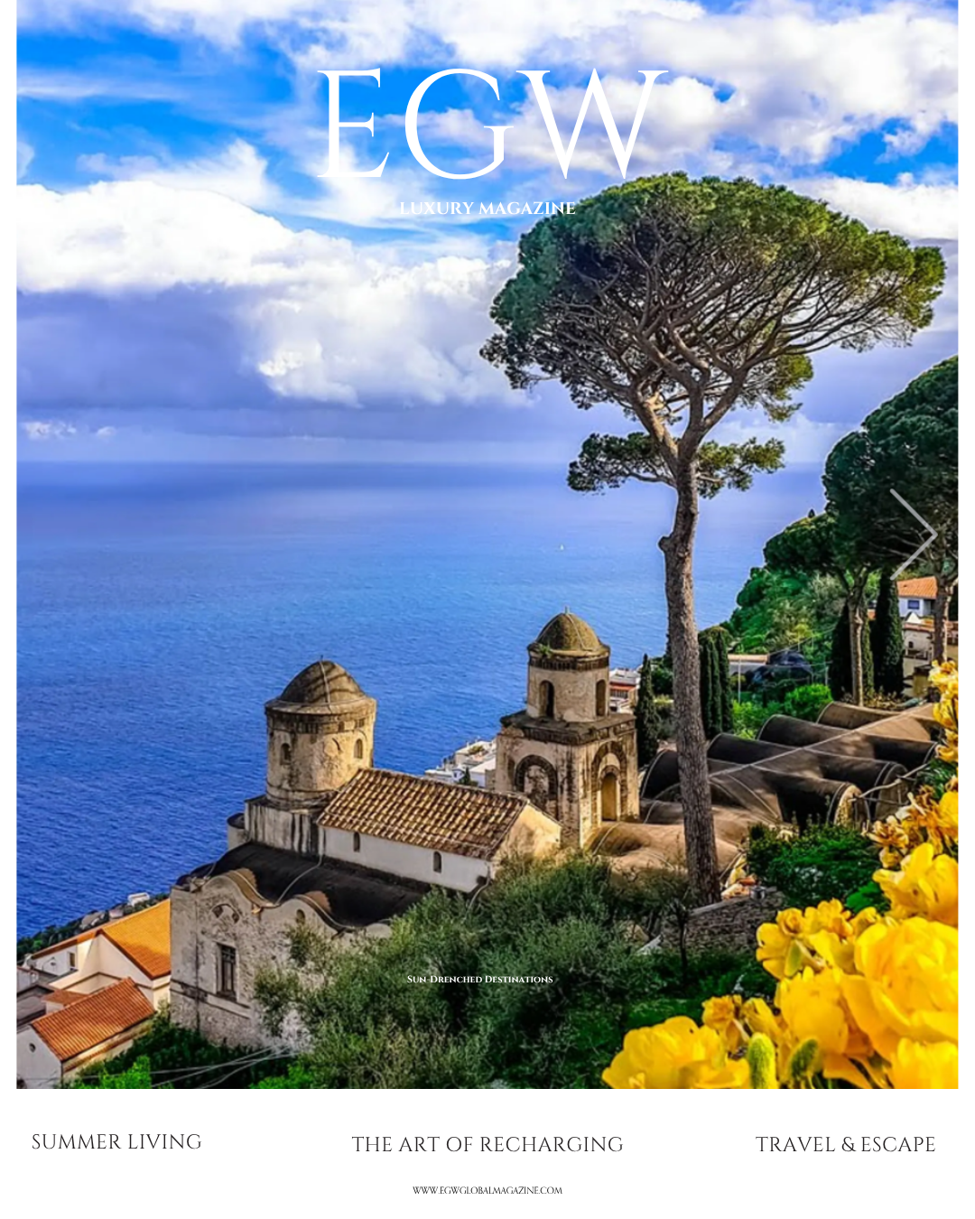 Scenic coastal landscape with ancient stone buildings, lush green trees, and a tall pine tree overlooking the sea, under a partly cloudy sky.