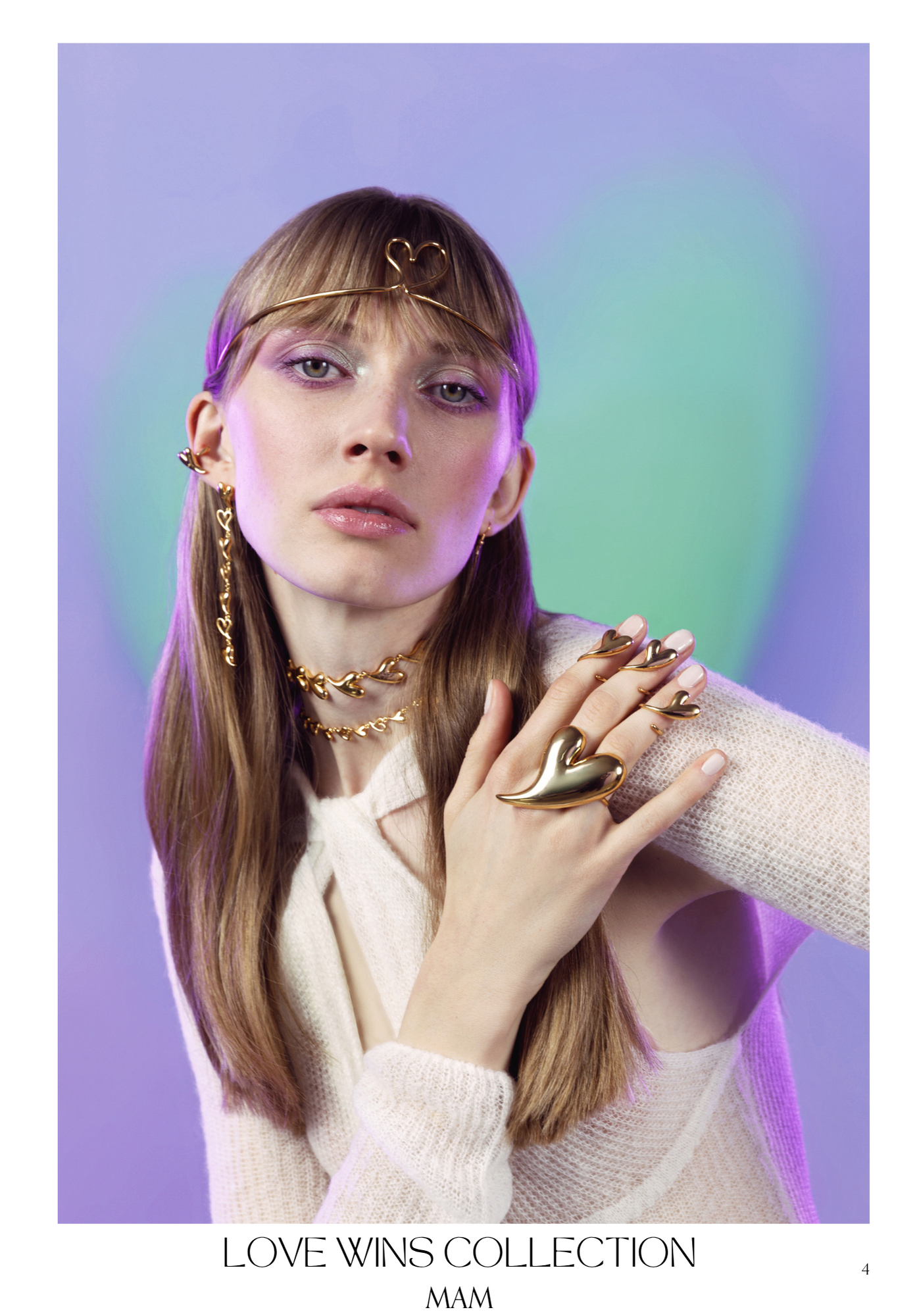A woman with long brown hair and blue eyes wearing gold jewelry, including a headband with a heart shape, earrings, layered necklaces, and rings. She has pastel-colored eyeshadow and poses with her hand near her lips against a purple background. The 