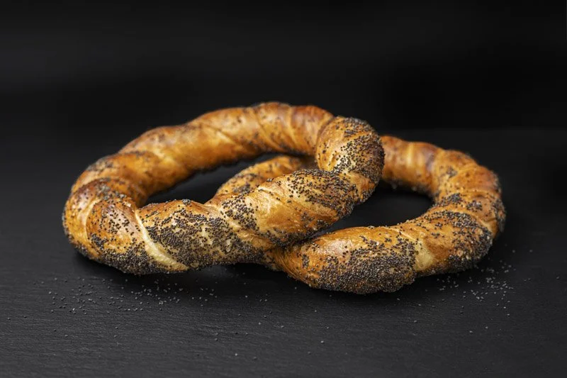 Două bagele cu semințe de mac pe o suprafață neagră.