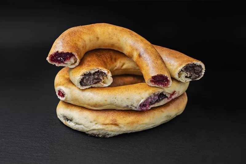 O grămadă de trei bagele cu umplutură de fructe de pădure pe o suprafață neagră