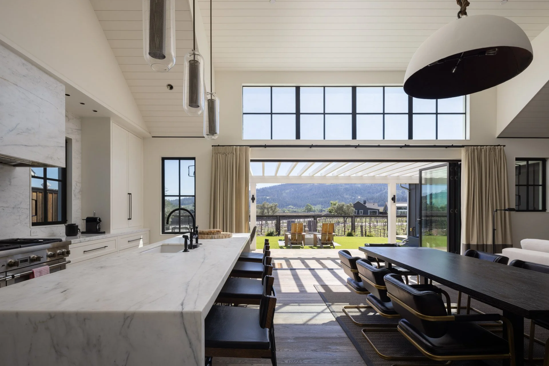 Open-concept kitchen and dining area with large sliding doors leading to a patio and scenic outdoor view of mountains and clear sky