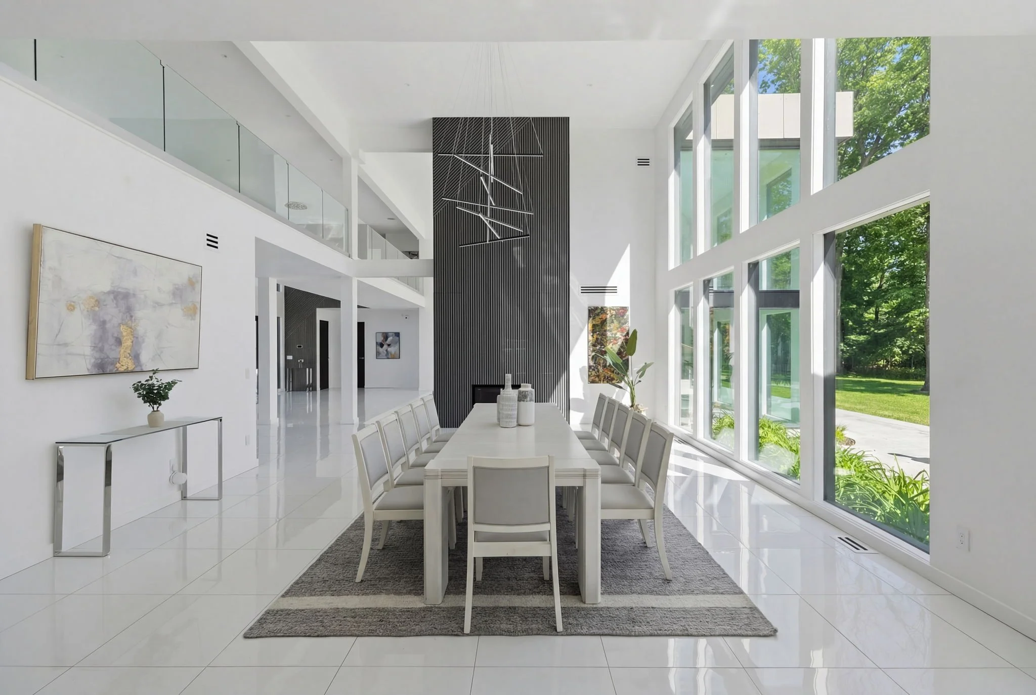 Modern dining room with white table and chairs, large windows, black textured accent wall, and minimalist decor.