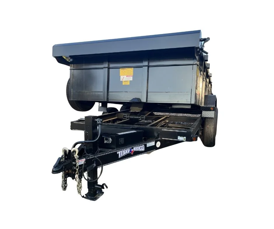 Black hydraulic dump trailer, attached to a hitch, isolated on a white background.