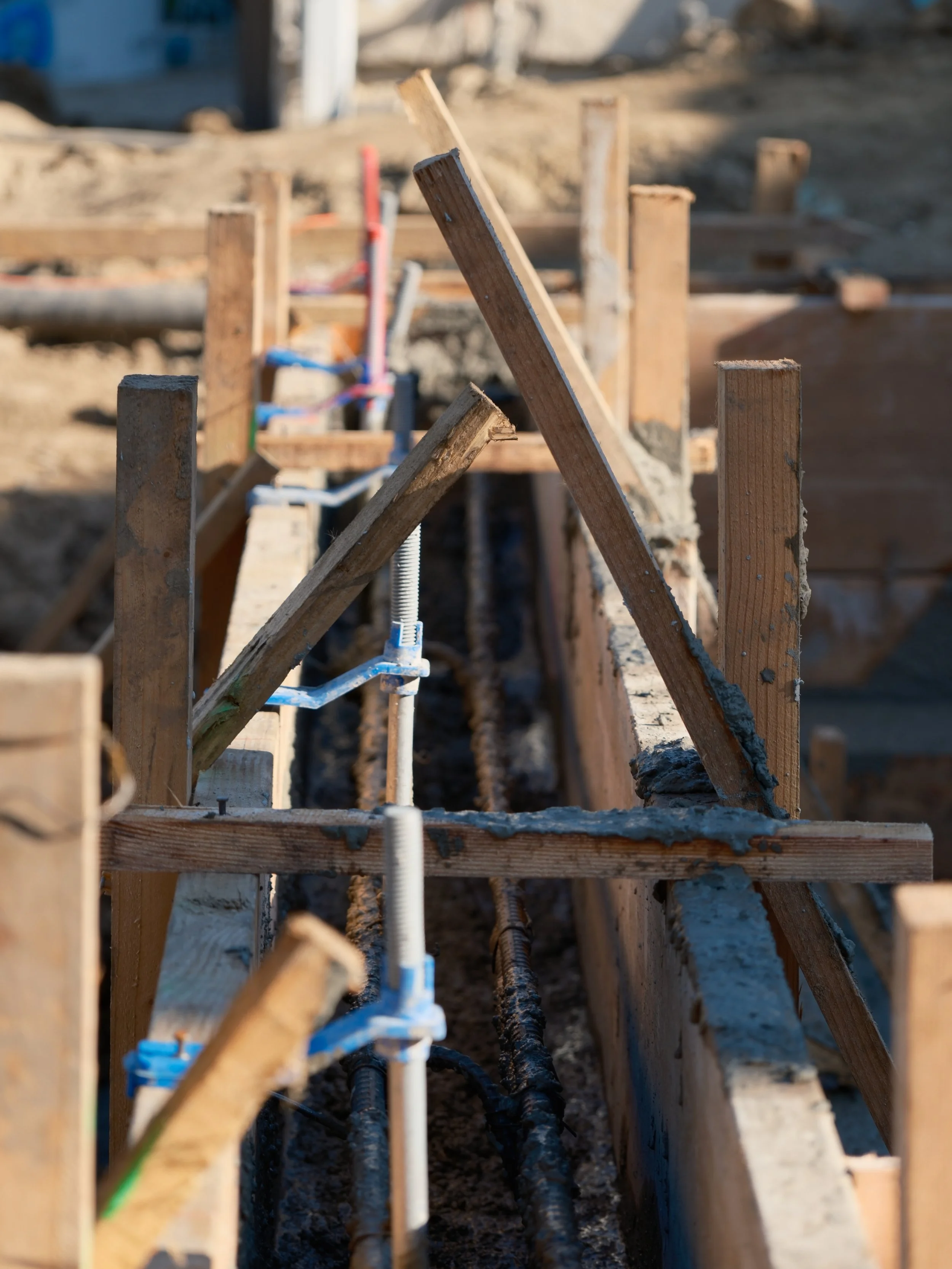 Construction site with wooden framework, pipes, and wires for building foundation or underground utilities.