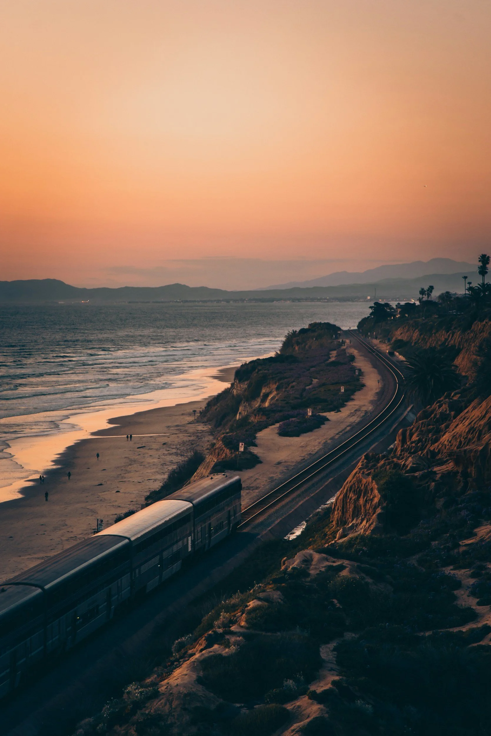 A train traveling down the California coast at sunset.