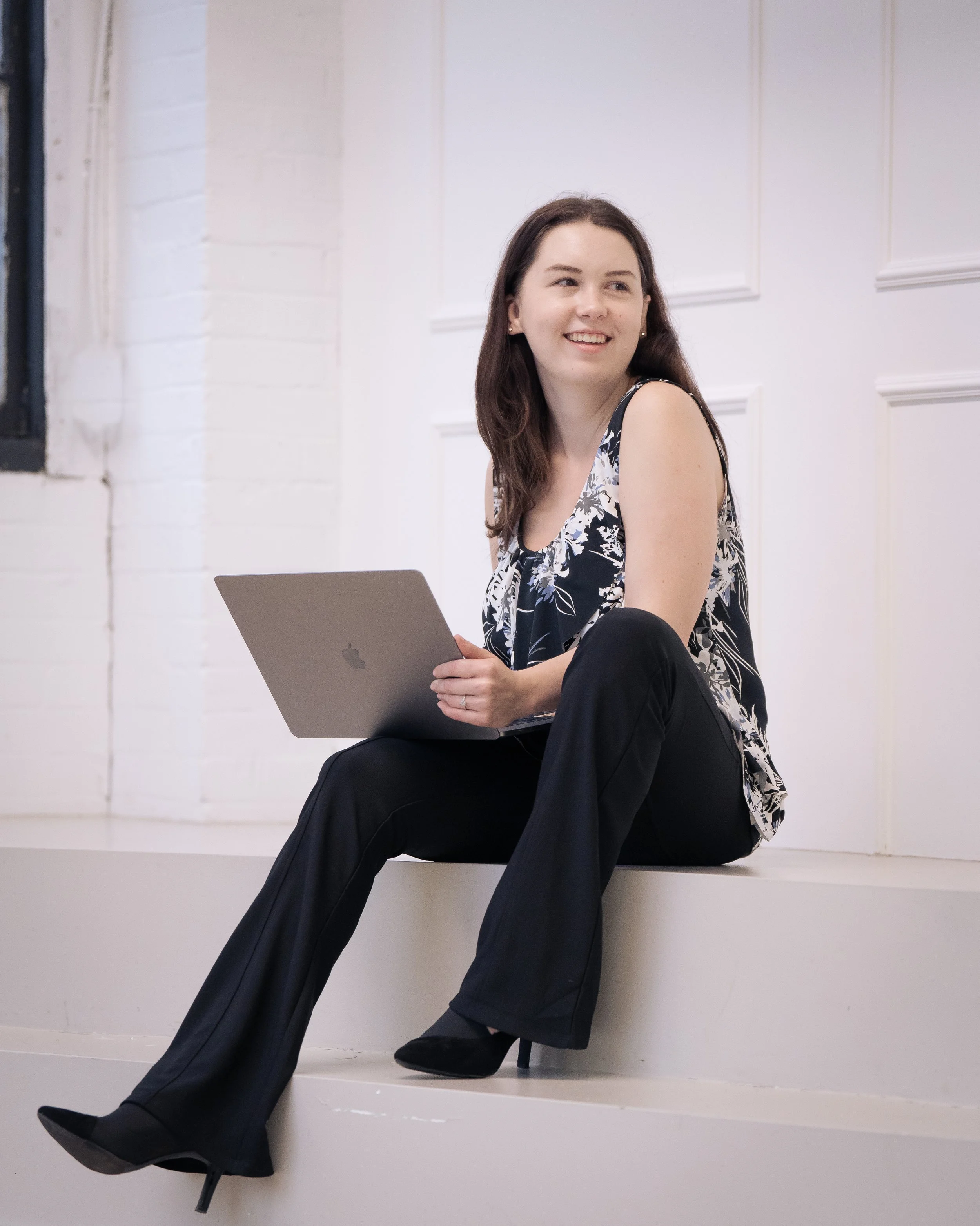 Tamara (content strategy expert) is sitting and holding a laptop while looking to the side