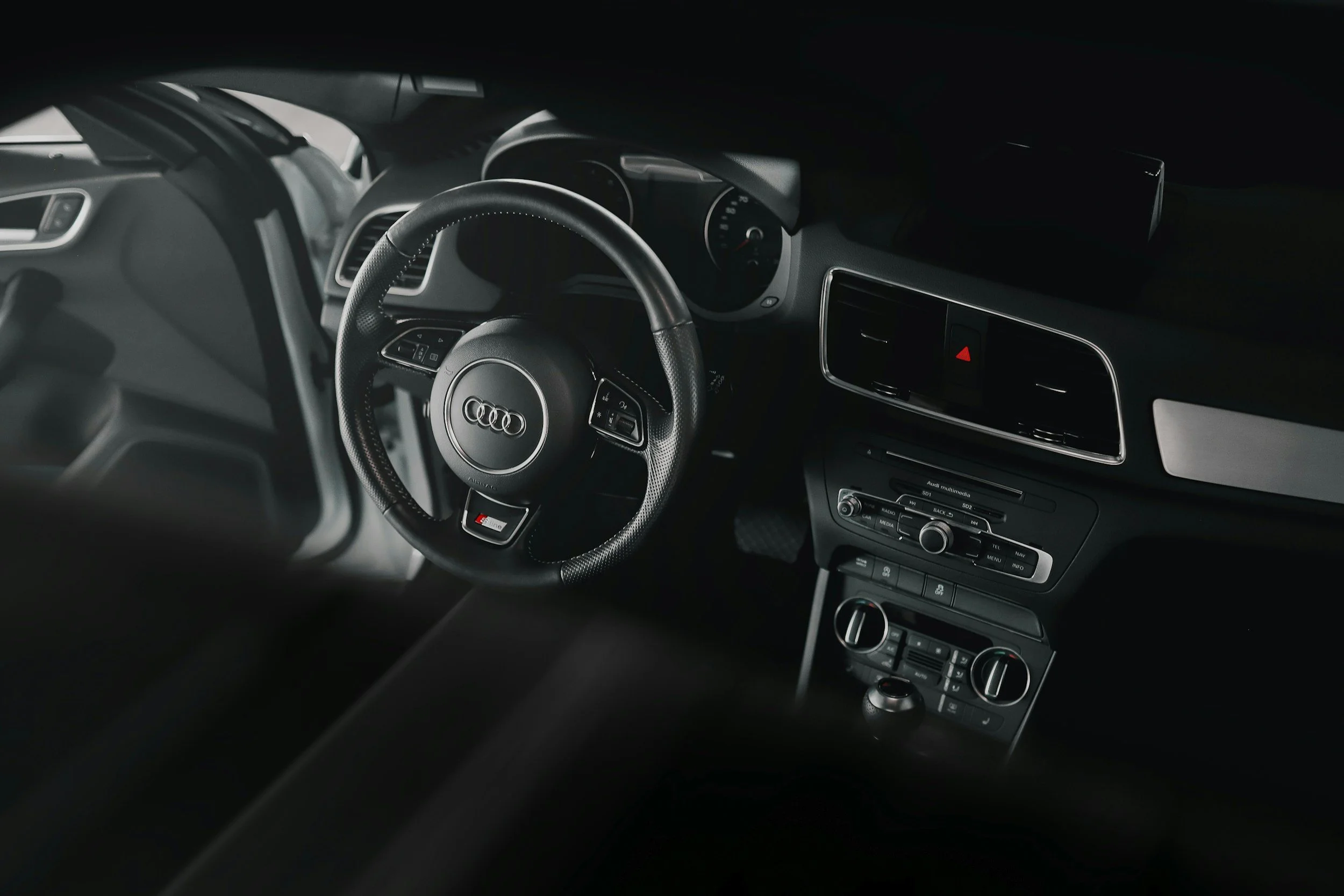 Interior view of a black Audi car dashboard, showing steering wheel, central console, and dashboard controls.