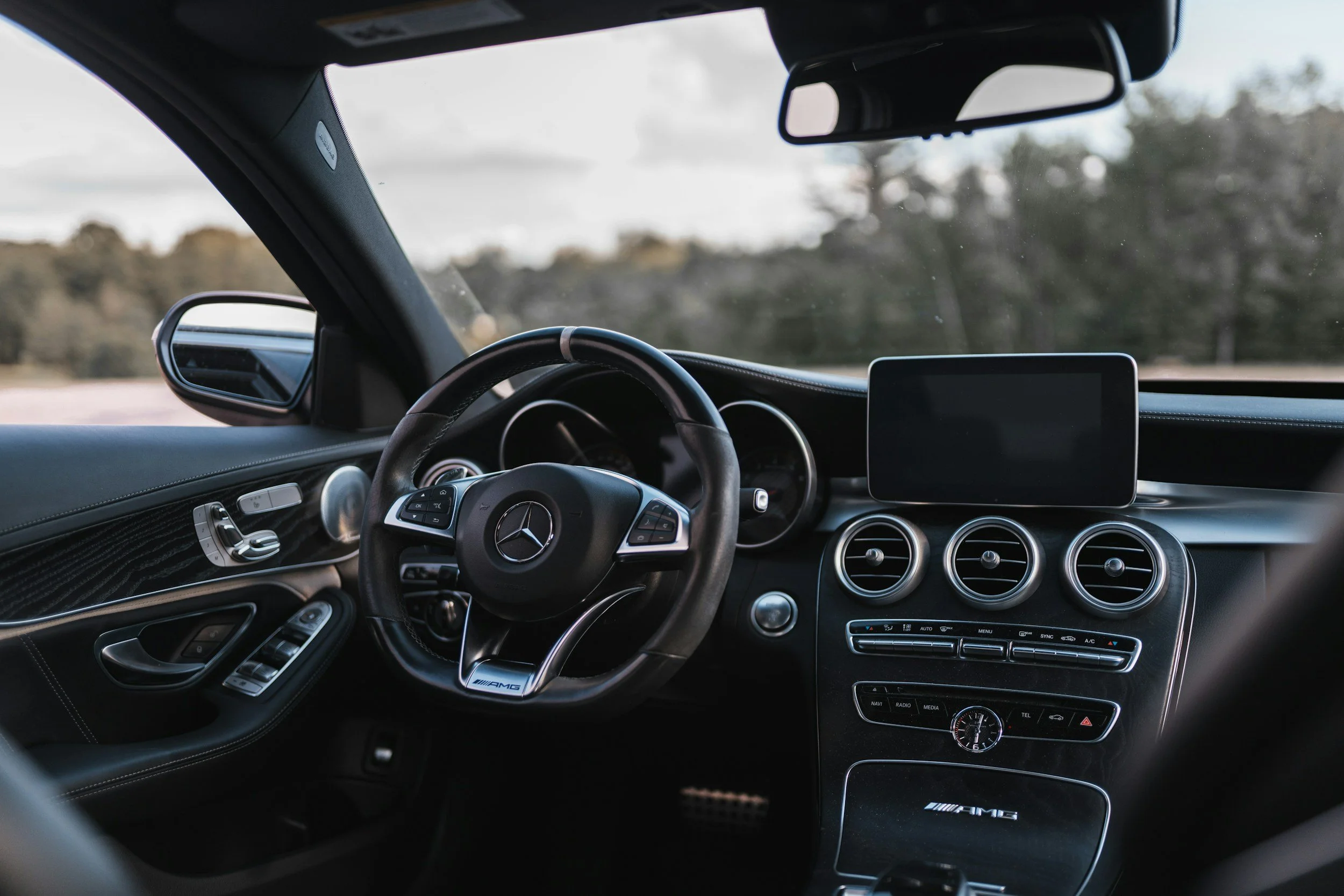 Interior of a Mercedes-Benz car showing the steering wheel, dashboard, and control panel with a digital screen.