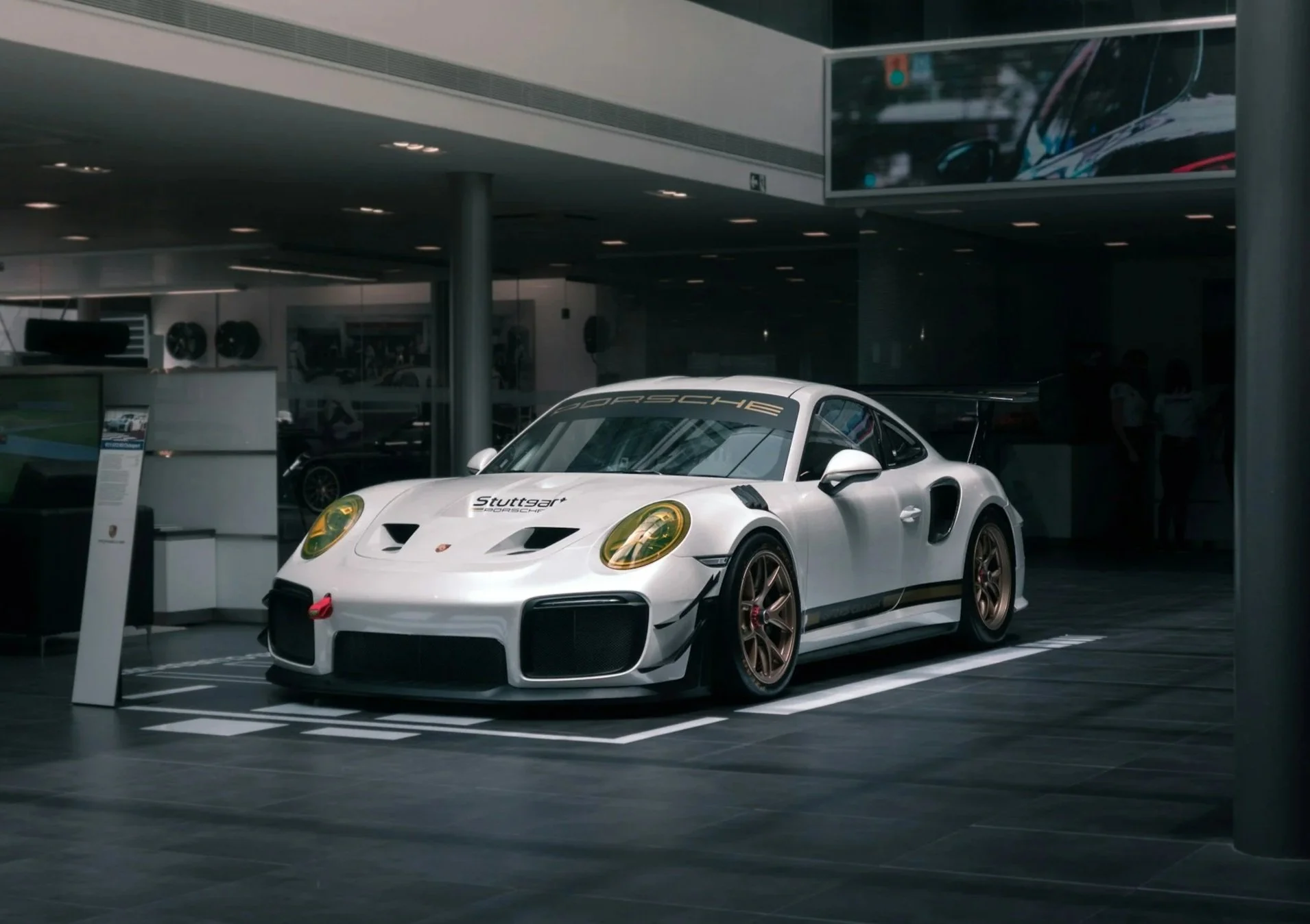 A white Porsche sports car on display inside a showroom.