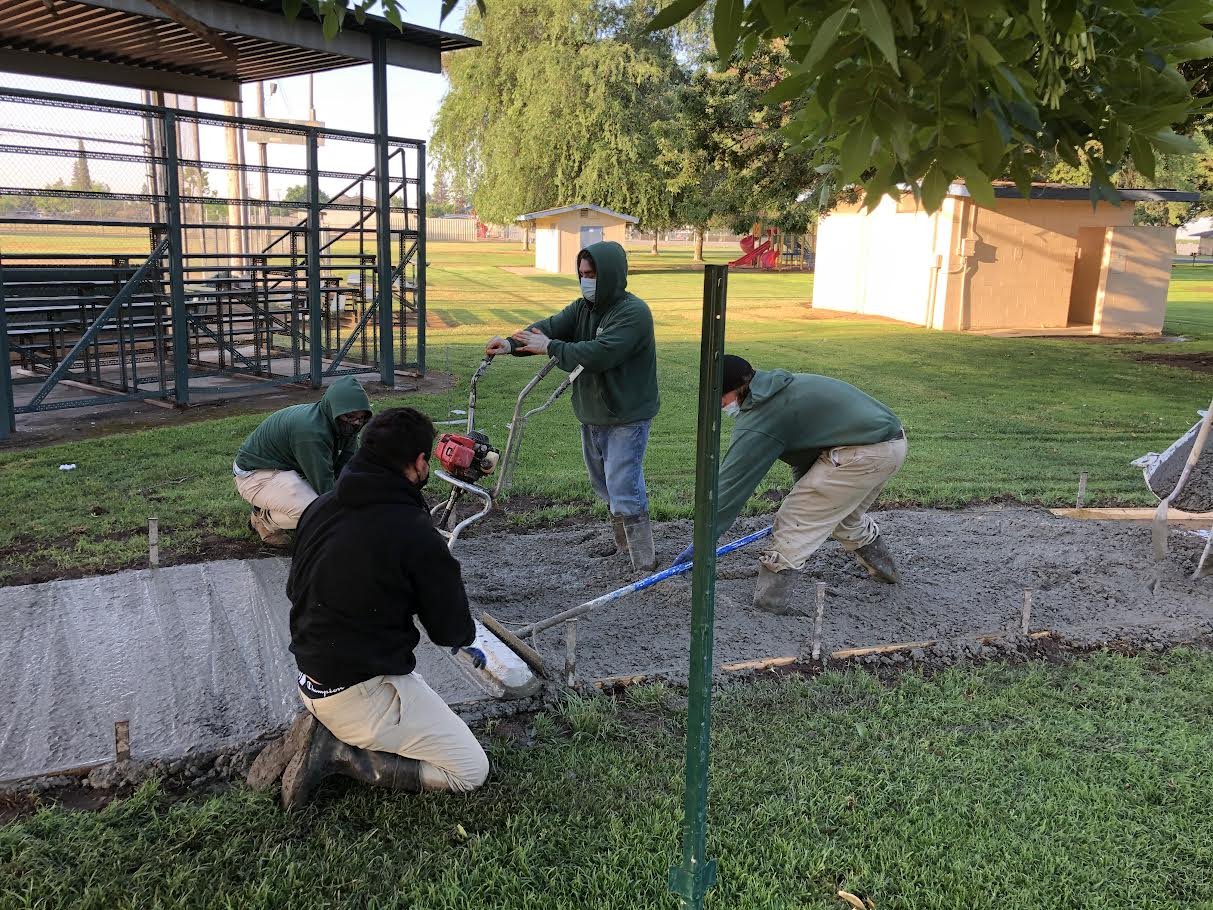 four men working on creating a new concrete path
