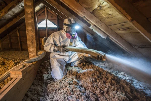 man in weatherization gear weathering an attic