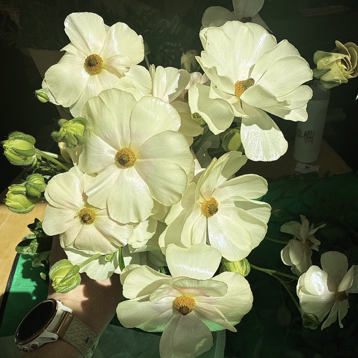 A bouquet of pale yellow flowers with dark centers, some buds, and green leaves.