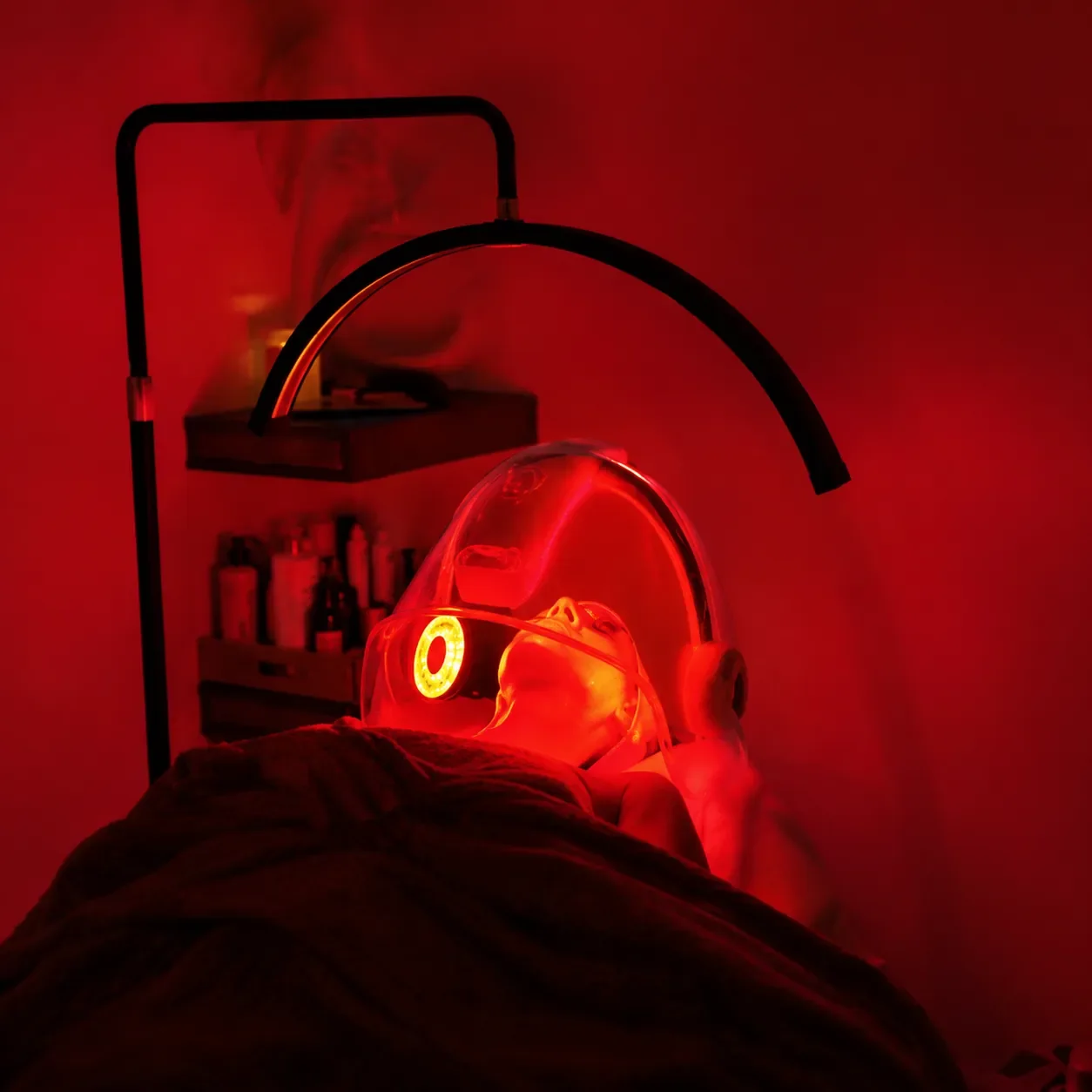 Client receiving a facial treatment under red LED light.