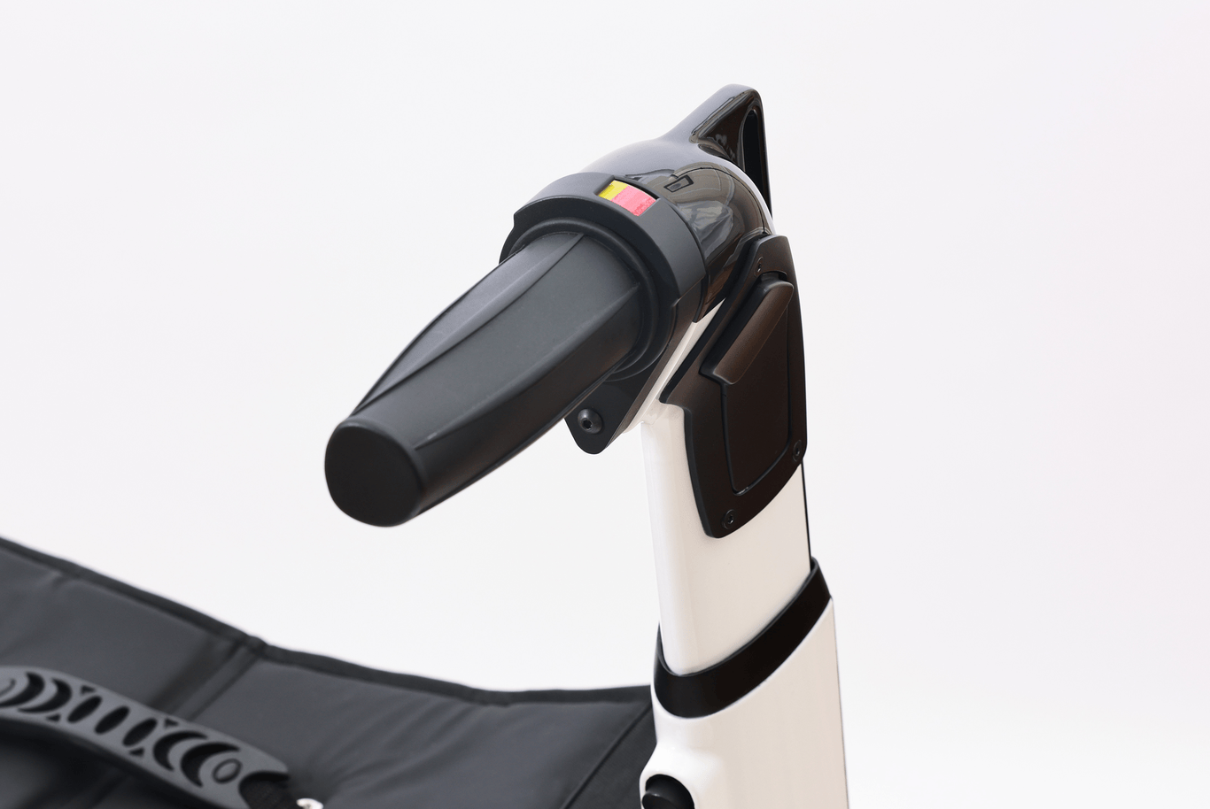 Close-up of the handle and control panel of a stair lift chair with black armrest and safety strap.