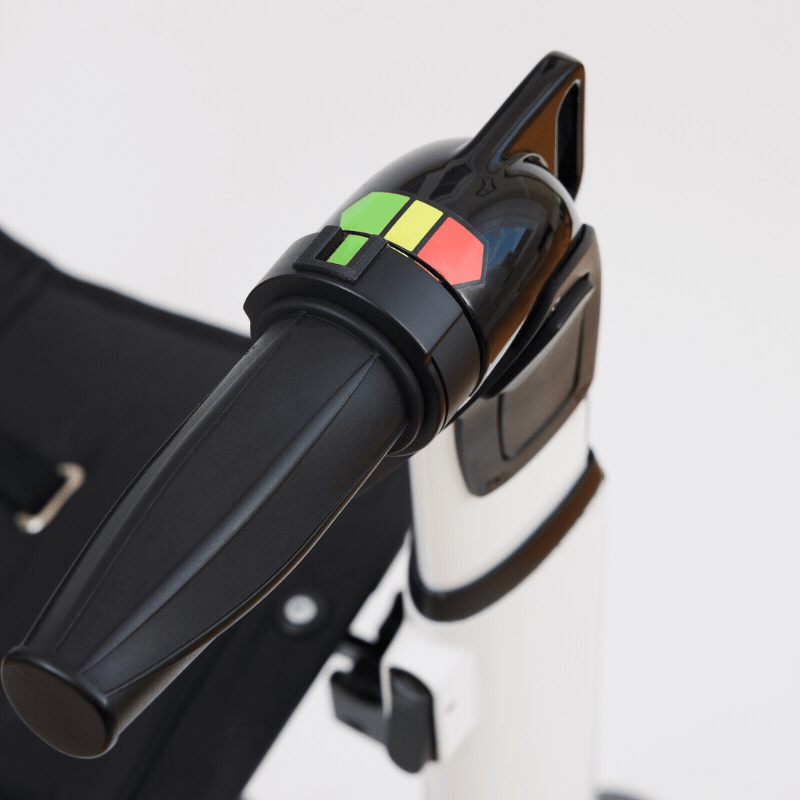 Close-up of a black suitcase with a black plug-in car charger attached to it, placed on a white surface.
