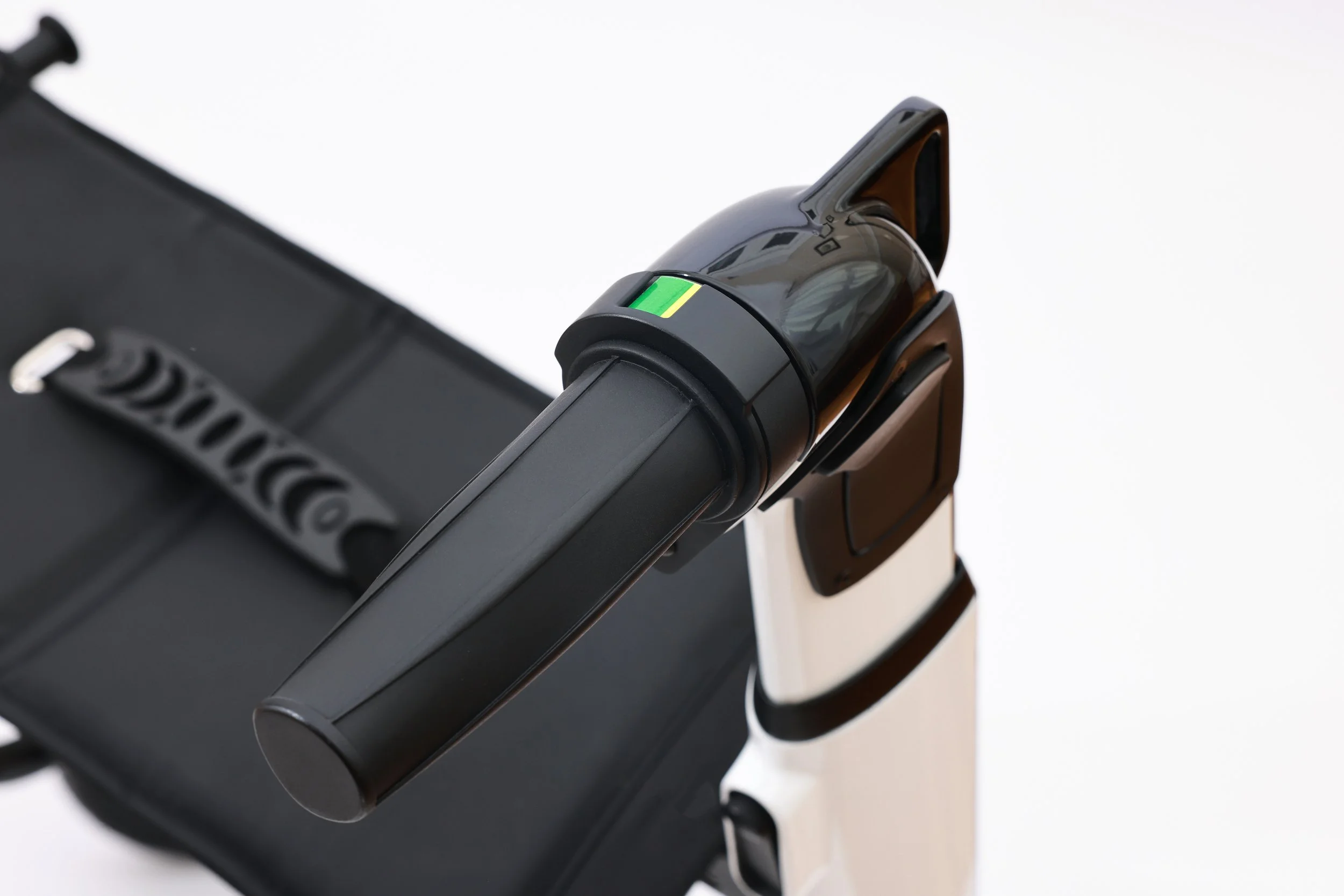 A portable handheld scanner with a black body and a green indicator on top, resting on a black surface or case.