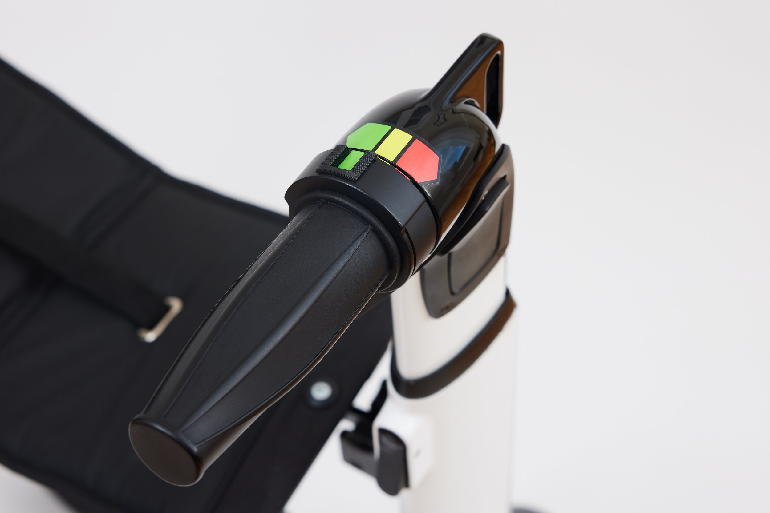 A portable handheld scanner with a black body and a green indicator on top, resting on a black surface or case.