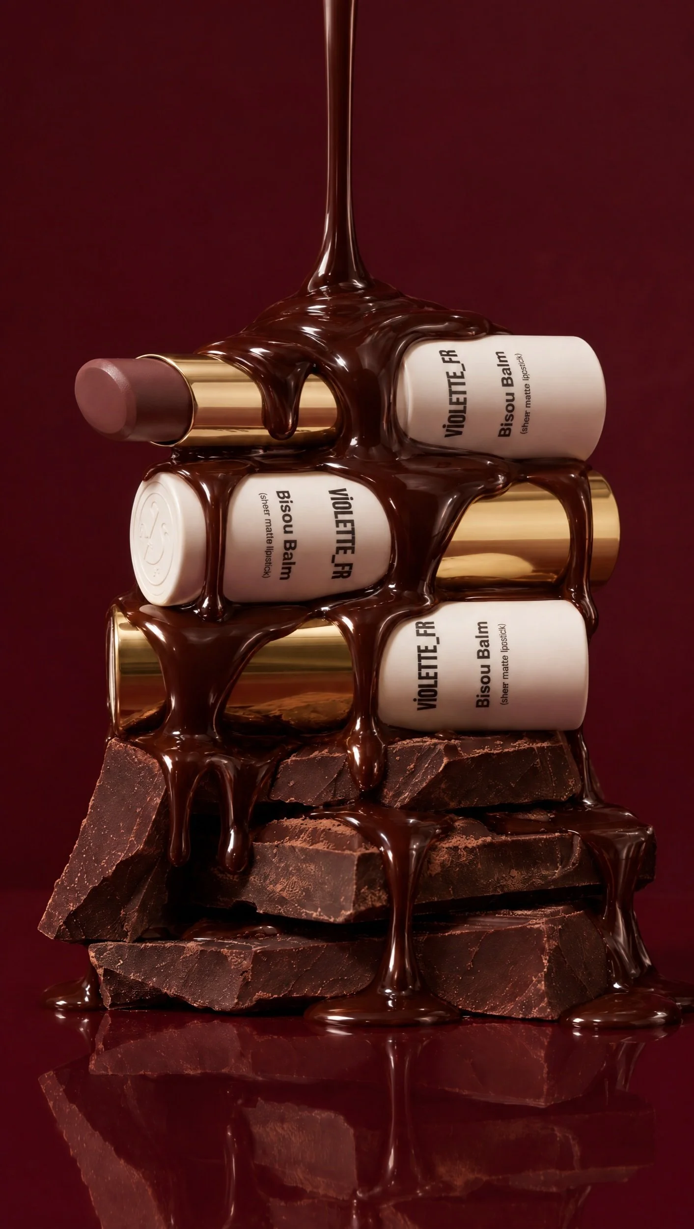 Melted chocolate pouring over a stack of Violette_FR Bisou Balm lipsticks and chocolate chunks