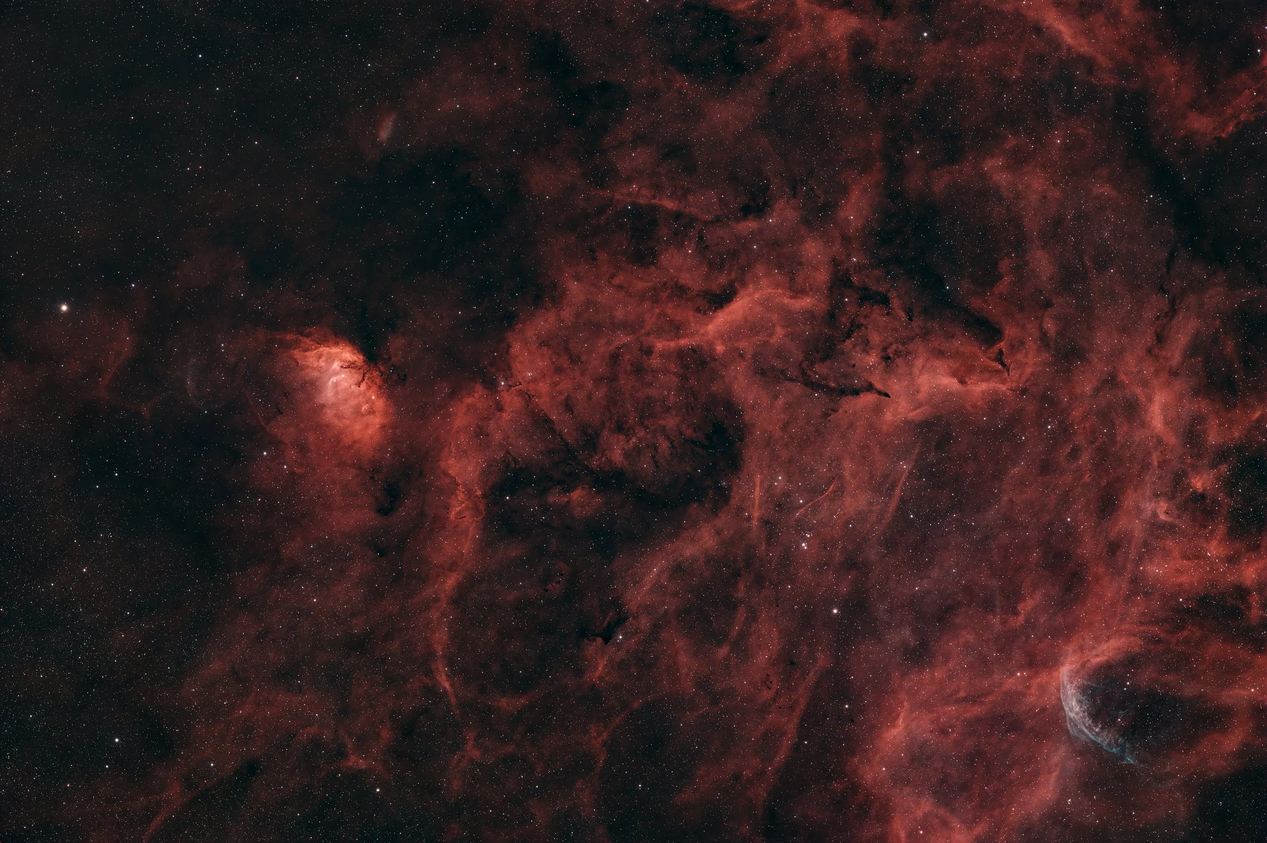 A detailed view of a red and black nebula in space with numerous stars scattered throughout.